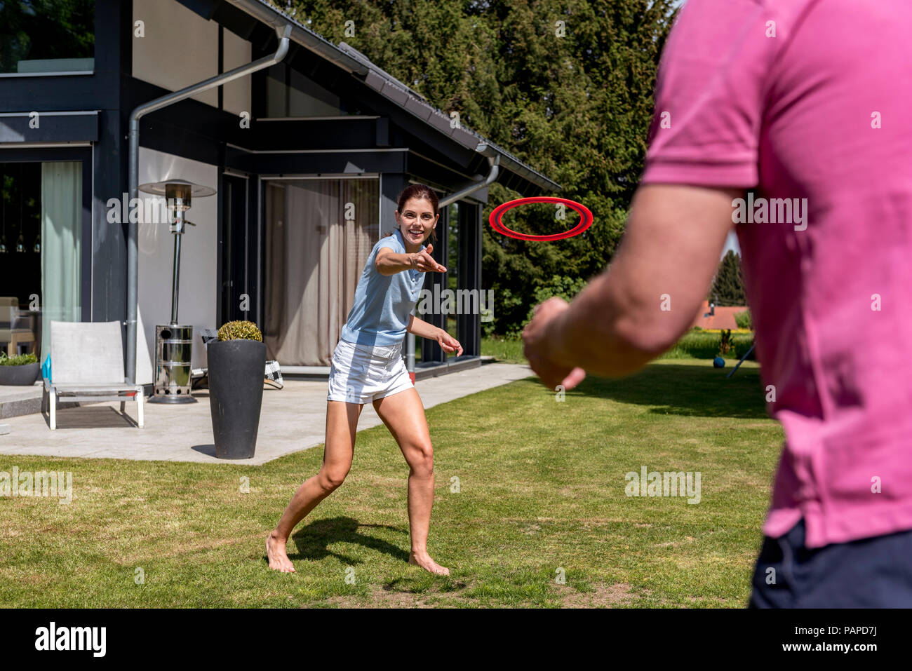 Heureux couple jouant avec disque volant dans le jardin de leur maison Banque D'Images Heureux couple jouant avec disque volant dans le jardin de leur maison Banque D'Images