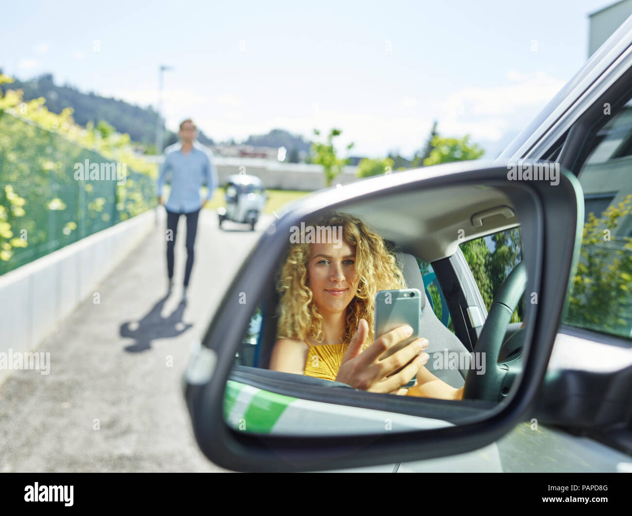 Smiling young woman using cell phone en voiture électrique Banque D'Images