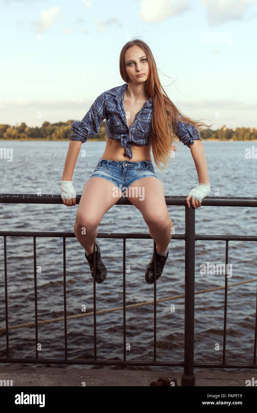 Jeune femme fighter est assis sur une clôture de fer sur la rive du fleuve. Banque D'Images