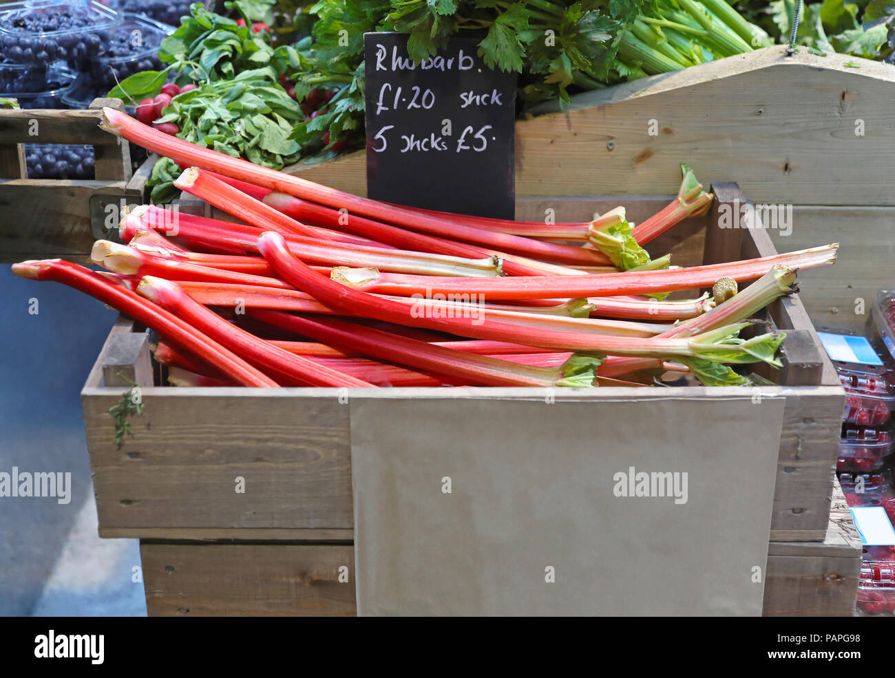 Les bâtonnets de rhubarbe rouge dans la caisse au farmers market Banque D'Images