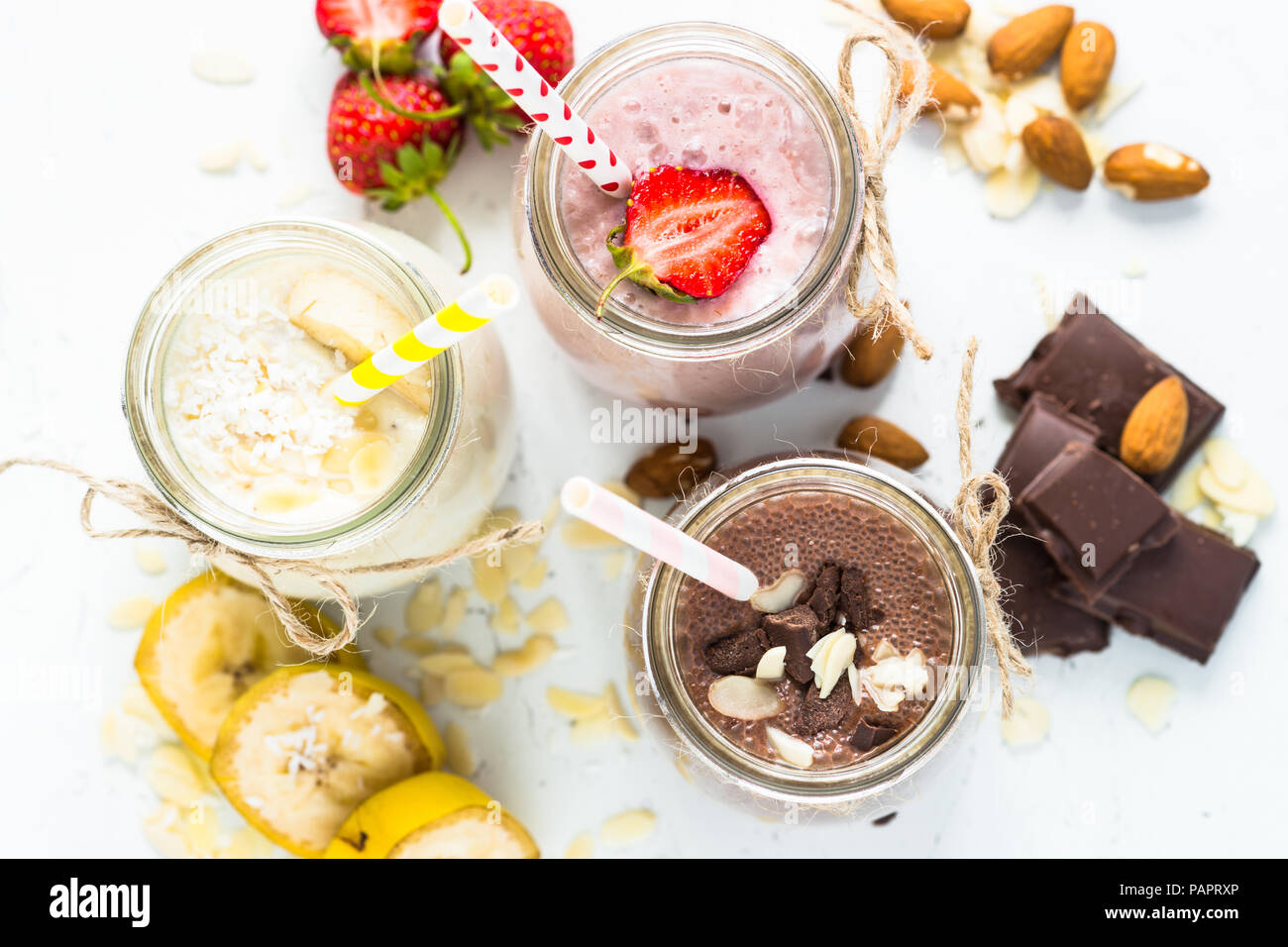 Ensemble de milkshake en pots. Banane Chocolat et Fraise milkshakes avec les écrous et la noix de coco. Dessert d'été. Vue d'en haut. Banque D'Images