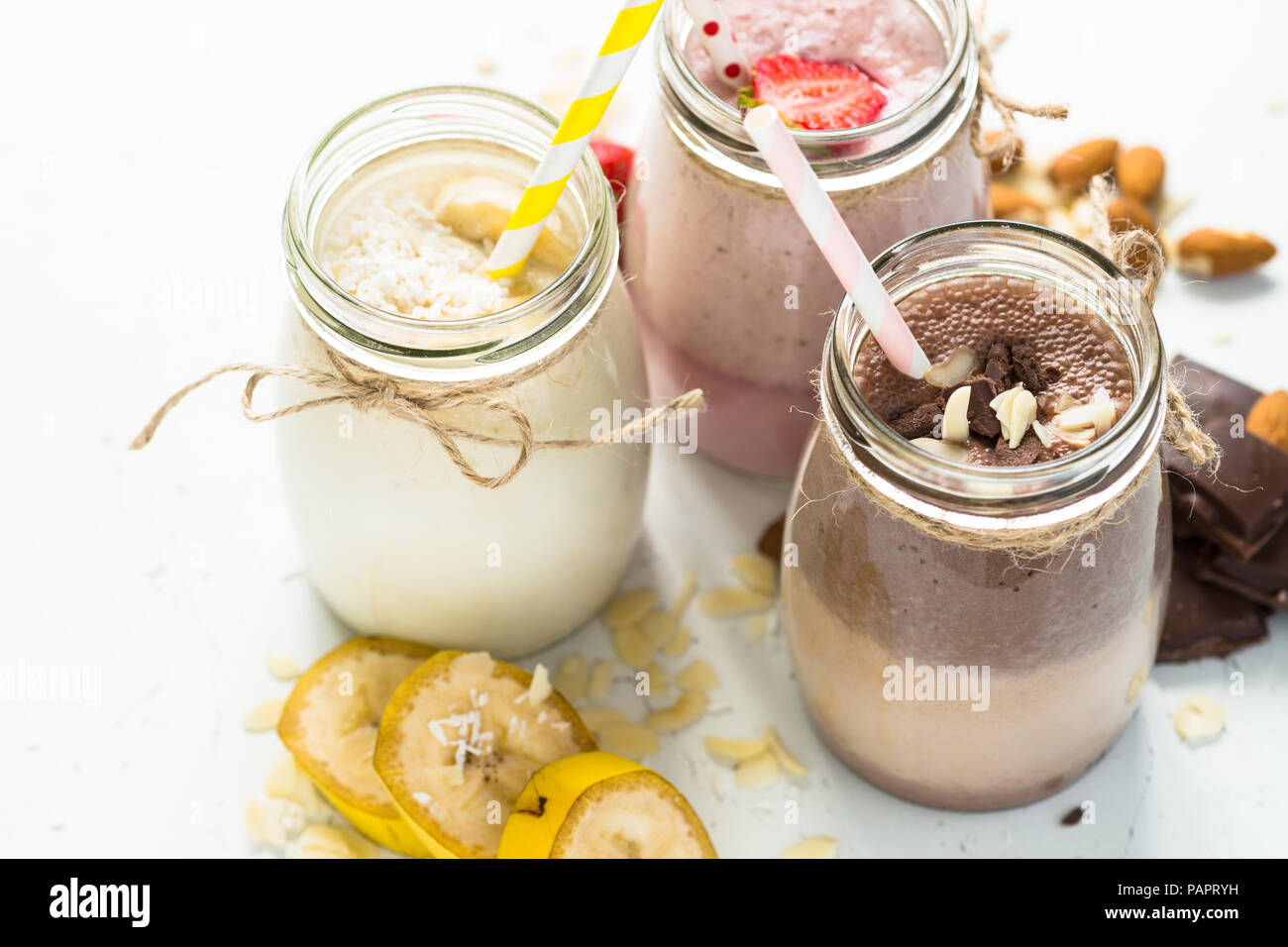 Ensemble de milkshake en pots. Banane Chocolat et Fraise milkshakes avec les écrous et la noix de coco. Dessert d'été. Alimentation saine. Banque D'Images