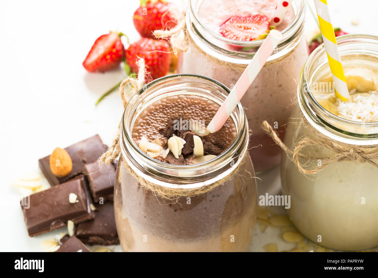 Ensemble de milkshake en pots. La banane, chocolat et fraise milkshakes aux noix et noix de coco. Dessert d'été. Alimentation saine. Banque D'Images
