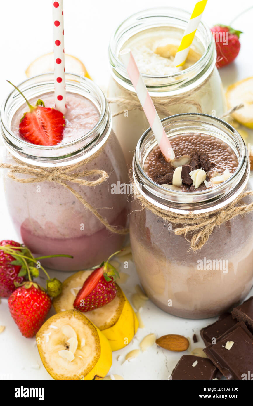 Ensemble de milkshake en pots. Banane Chocolat et Fraise milkshakes avec les écrous et la noix de coco. Dessert d'été. Alimentation saine. La verticale. Banque D'Images