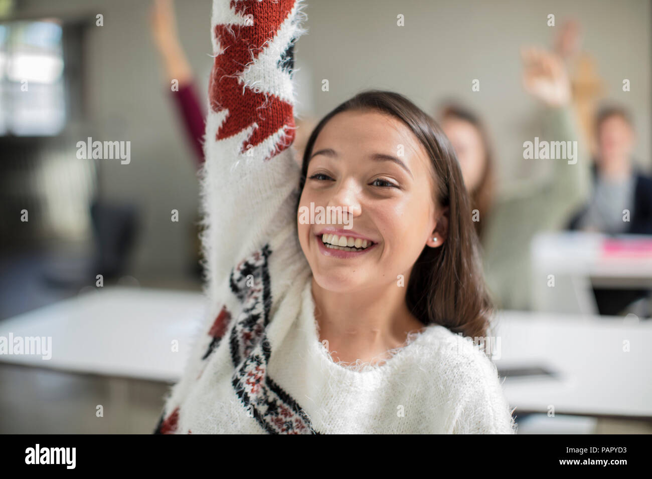 Smiling teenage girl raising hand in class Banque D'Images