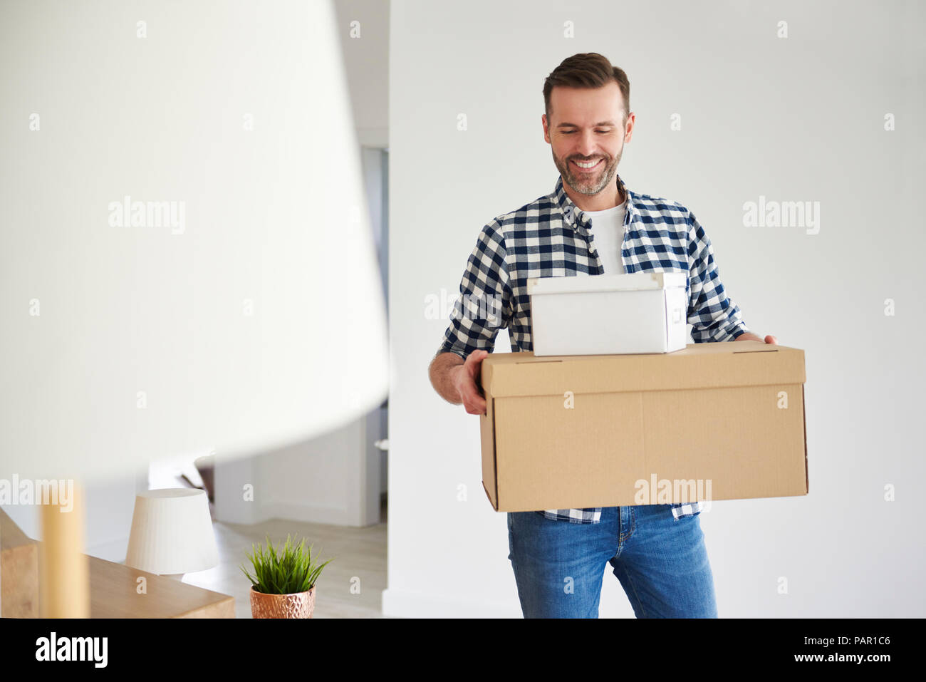 Homme heureux déménagement en nouvelle télévision carrying cardboard box Banque D'Images