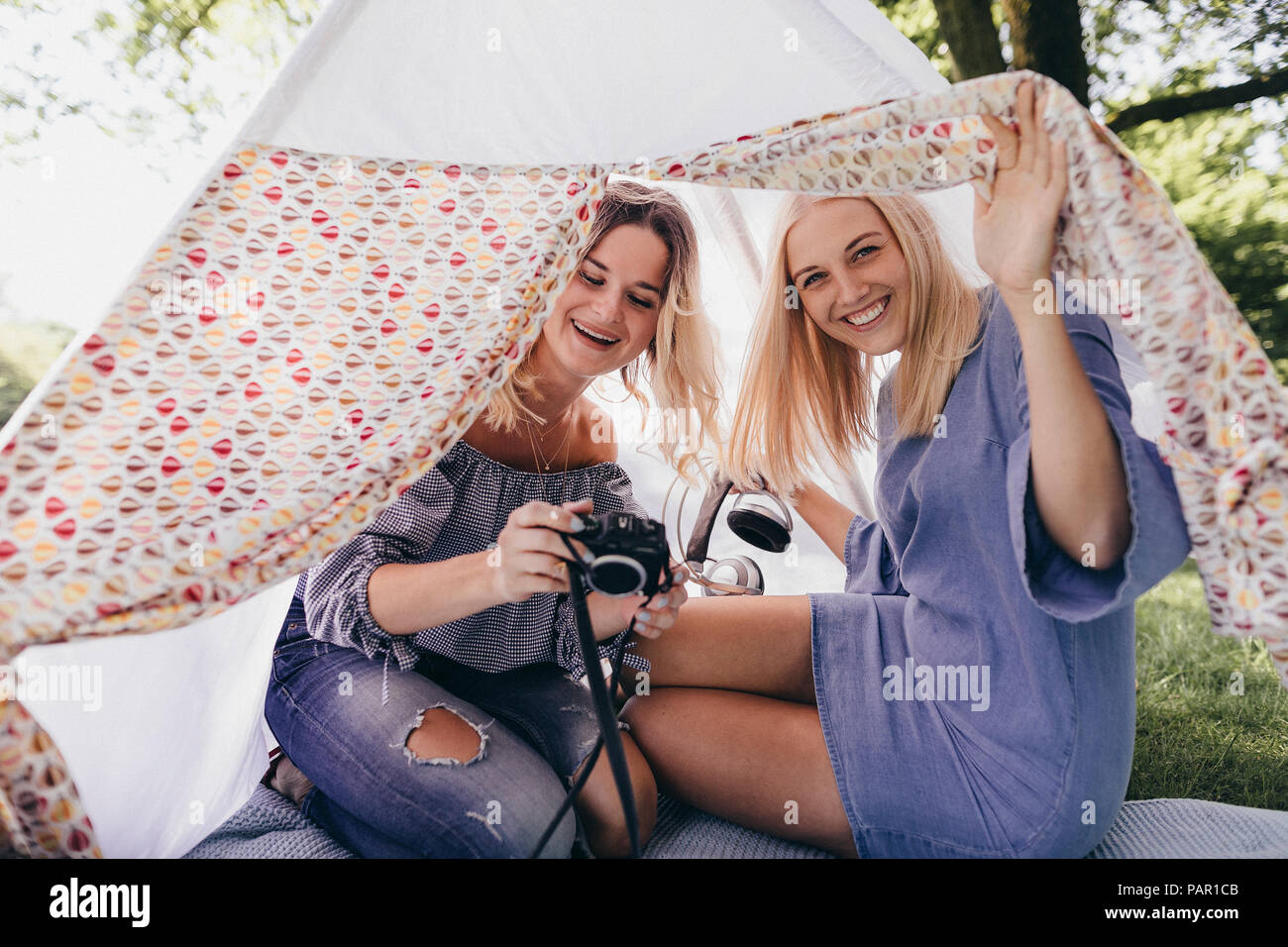 Deux jeunes femmes heureux avec l'appareil photo à l'ancienne dans un tipi dans un parc Banque D'Images