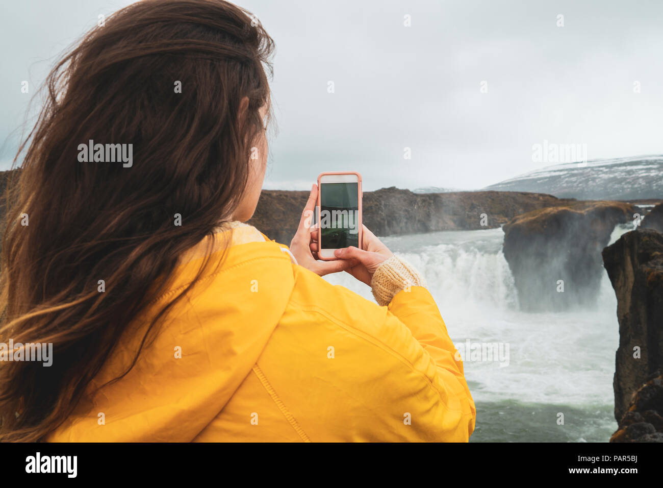 L'Islande, woman taking cell phone photo de cascade Godafoss Banque D'Images