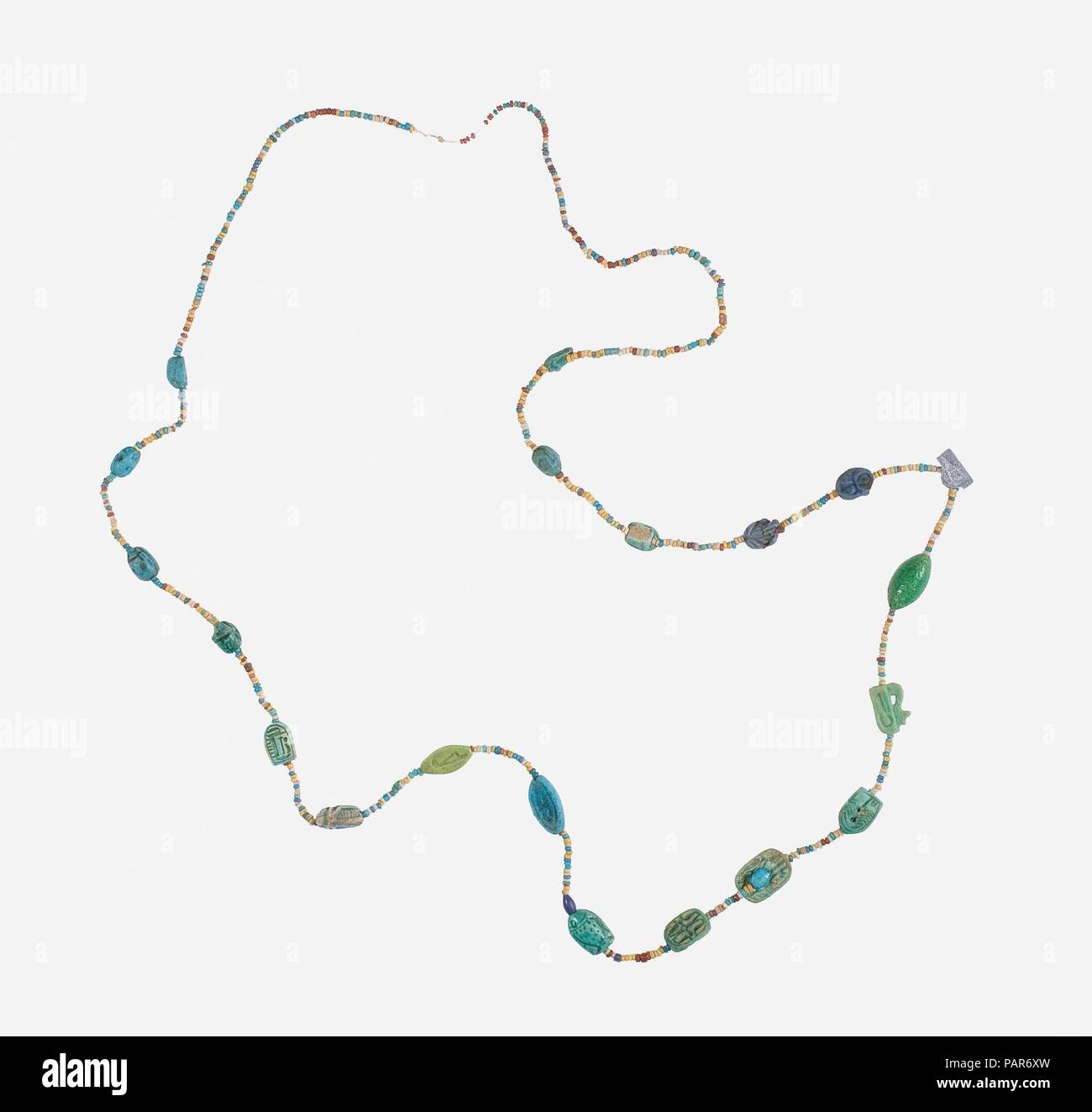 Collier de perles et des amulettes. Dimensions : 85 cm L. (33 7/16 po). Dynastie DYNASTIE : 18. Règne : règne d'Amenhotep III. Date : ca. 1390-1353 av. J.-C.. Cette chaîne de perles et les amulettes ont été trouvés dans le même dépôt avec une plus petite chaîne et un collier menat bien conservé. Les amulettes : plusieurs plaques ovales inscrits, amulettes joint à dossier sculpté dans la forme d'un homme accroupi, une souris, une sauterelle, deux grenouilles, et threefish. Deux dos ont décoré d'oudjat s-yeux, trois sont cowroids (amulettes en forme de cauris), et il y a cinq des scarabées. L'un des scarabées est inscrit sur la Banque D'Images