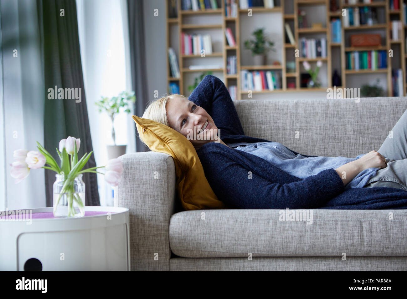 Woman relaxing at home, lying on couch Banque D'Images