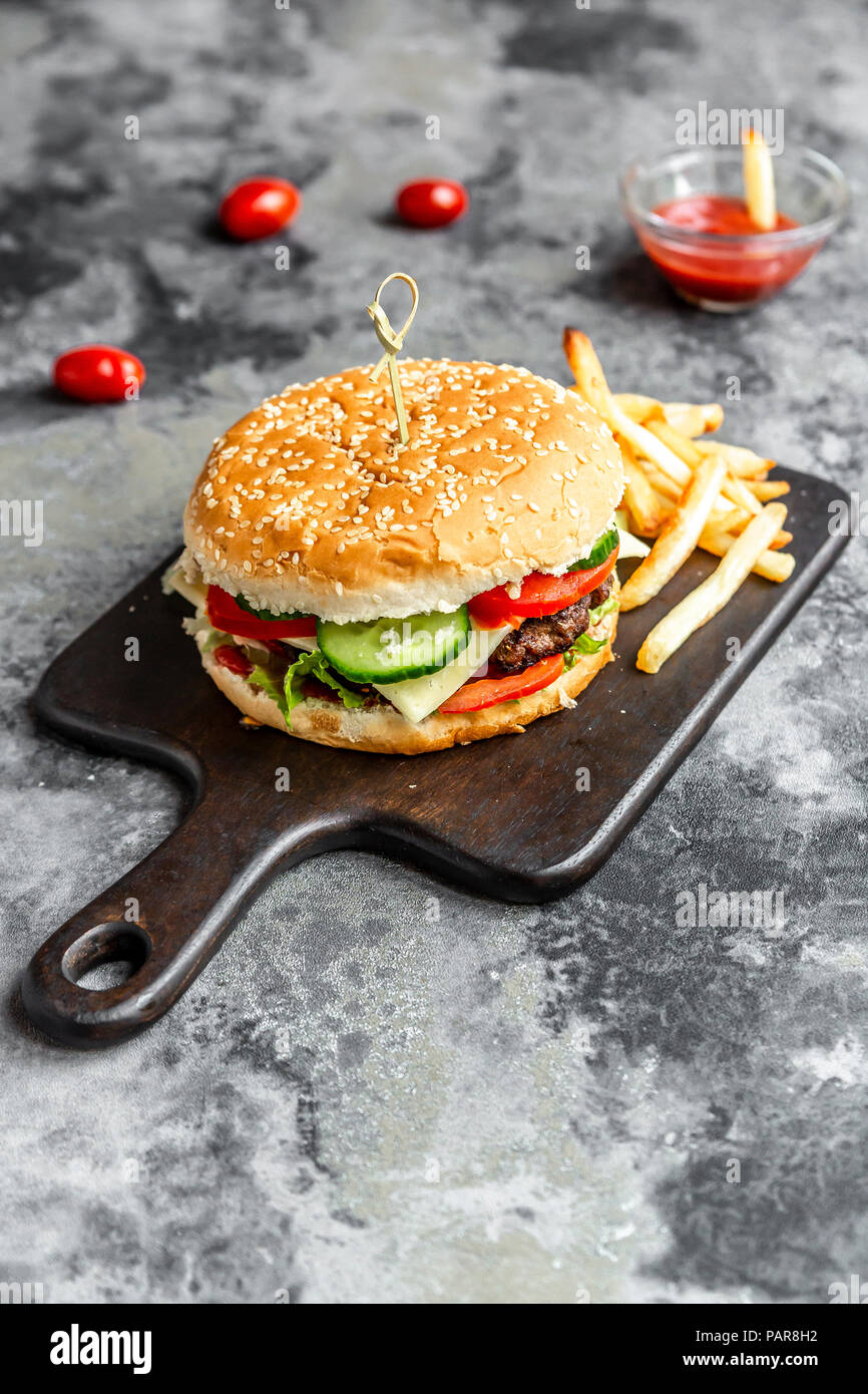 Hamburger fait maison avec du fromage, frites, ketchup et tomate Banque D'Images