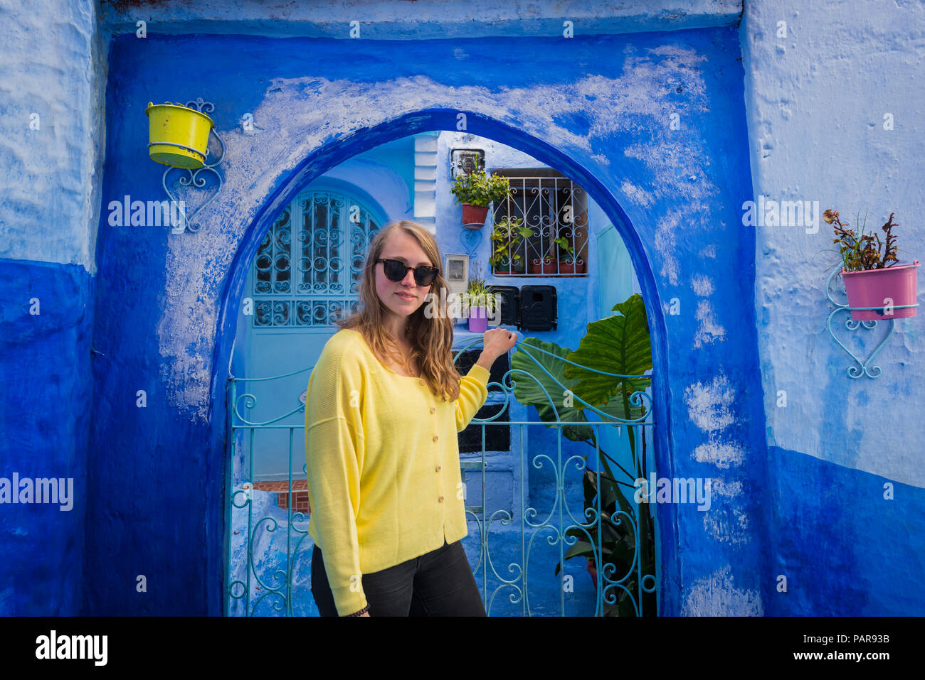 Jeune femme en face d'une porte, bleu façade de maison, vieille ville, Médina de Chefchaouen, Chaouen, Tangier-Tétouan, Maroc Banque D'Images