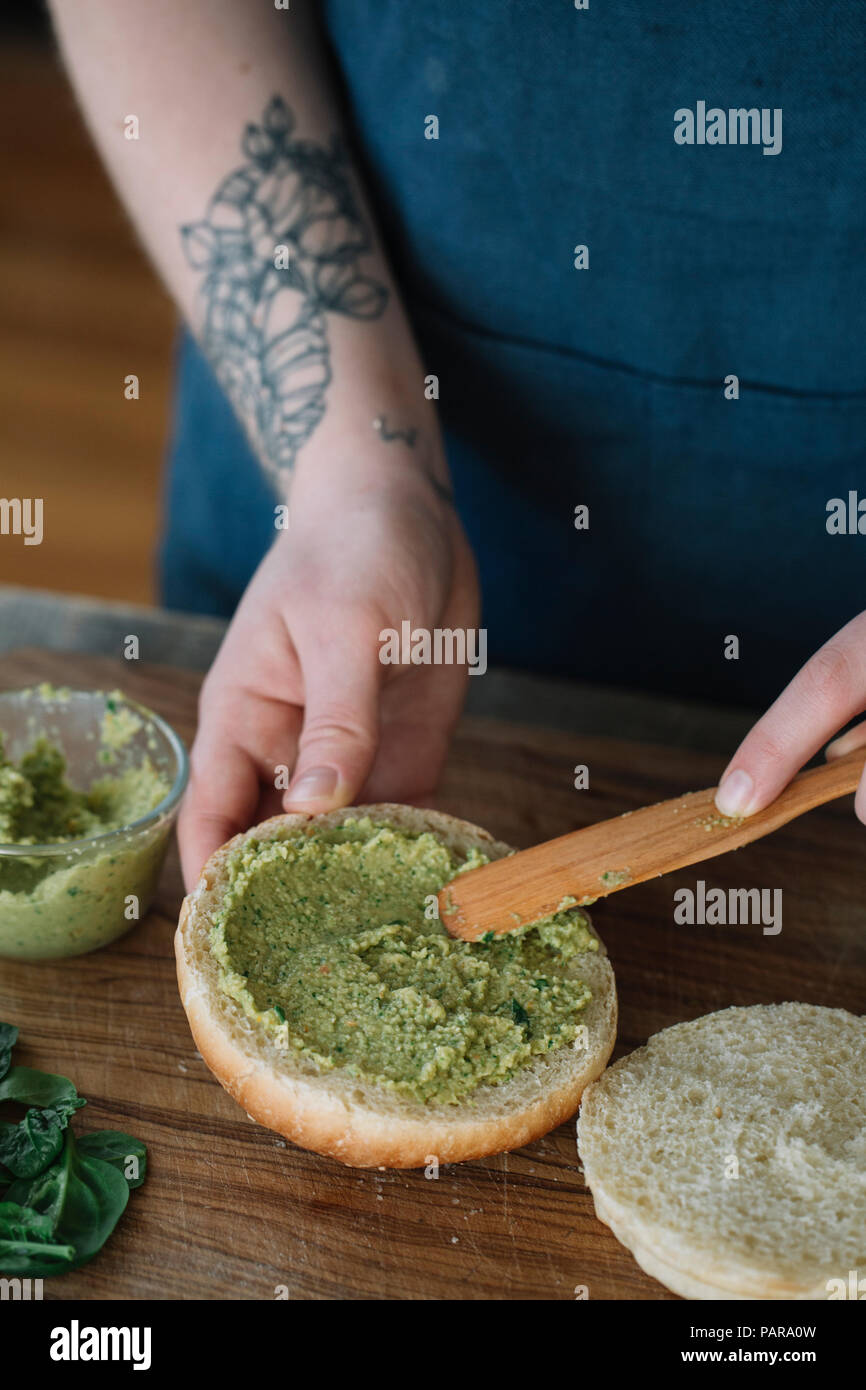 Femme préparant vegan burger, crème d'épandage sur pain Banque D'Images