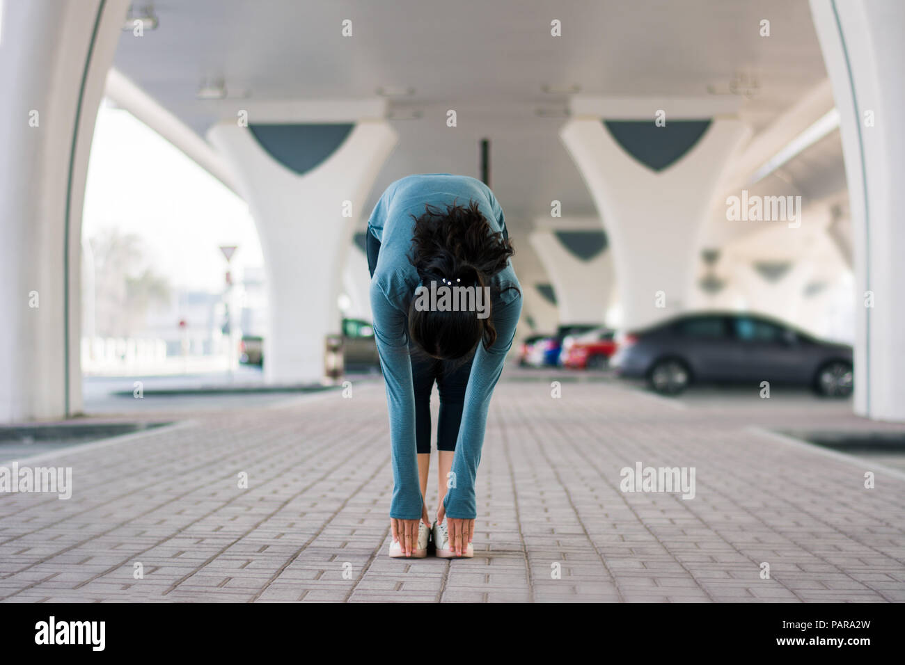 Girl étirements avant d'entraînement sur le terrain de stationnement en plein air Banque D'Images