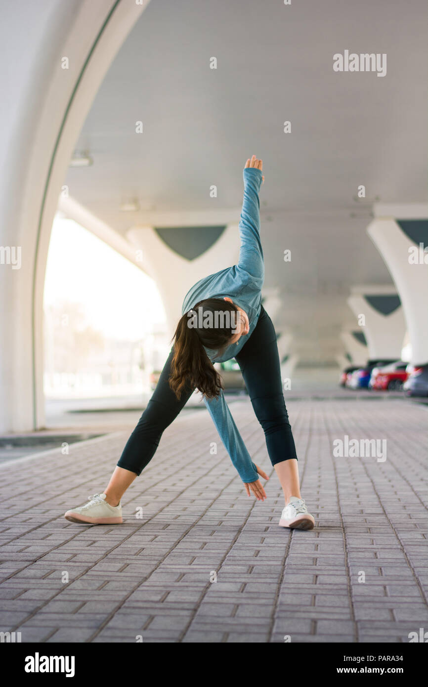 Girl étirements avant d'entraînement sur le terrain de stationnement en plein air Banque D'Images