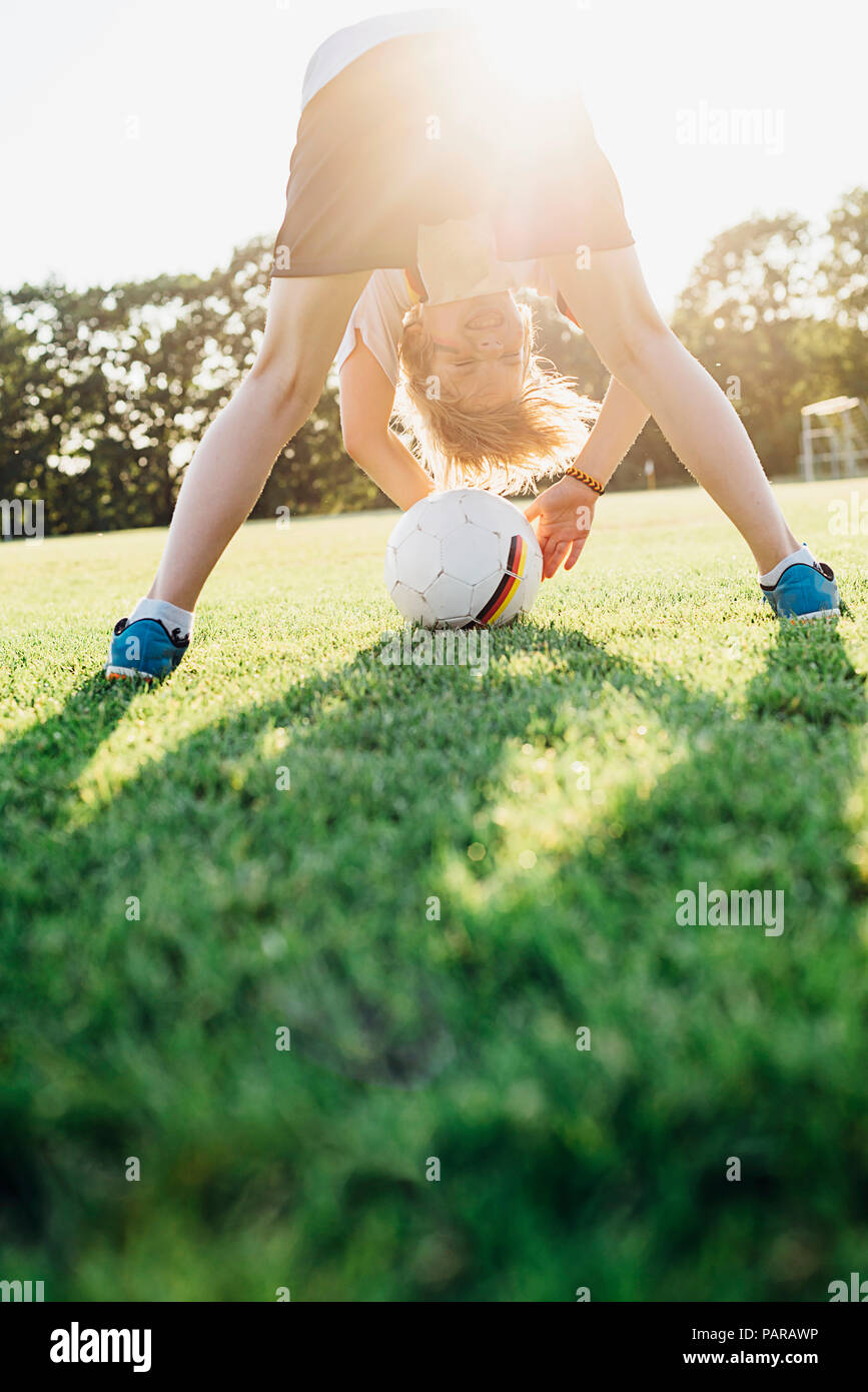 Garçon sur le terrain de football, se pencher, à l'intermédiaire de ses jambes Banque D'Images