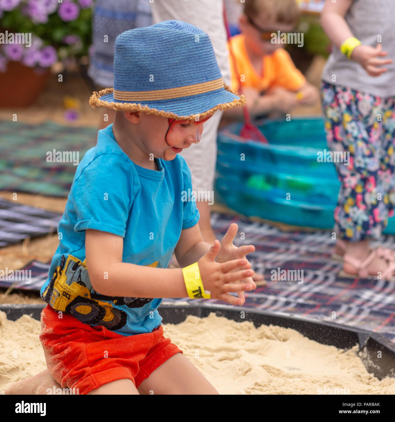 Jeune garçon portant un chapeau bleu jouant dans un bac à sable à un pays juste dans le Hampshire. Banque D'Images