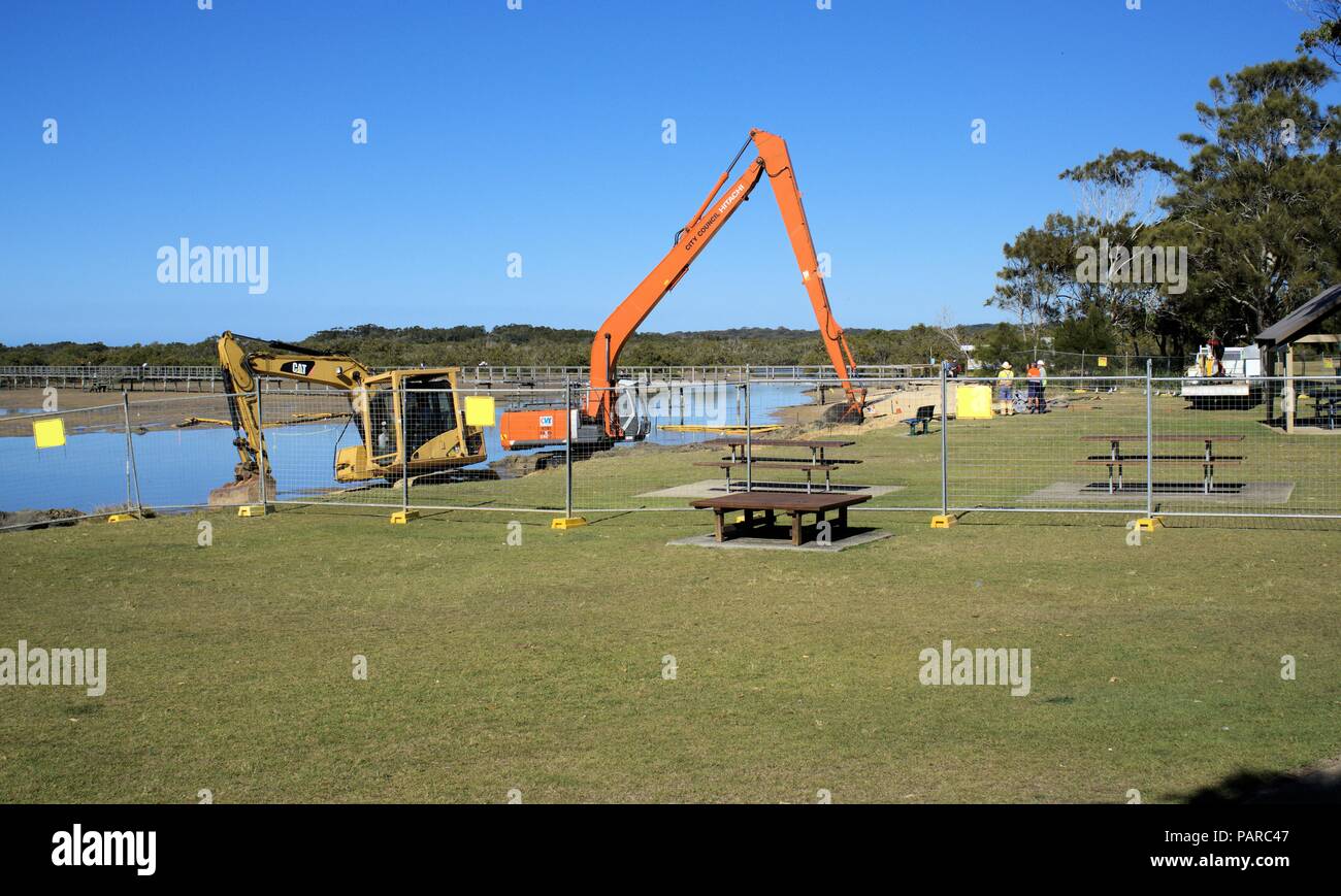 Pelle hydraulique ou digger crane dans l'eau en Australie, Coffs Harbour. Avec les travailleurs de la machinerie lourde dans l'action au lieu de travail. Banque D'Images