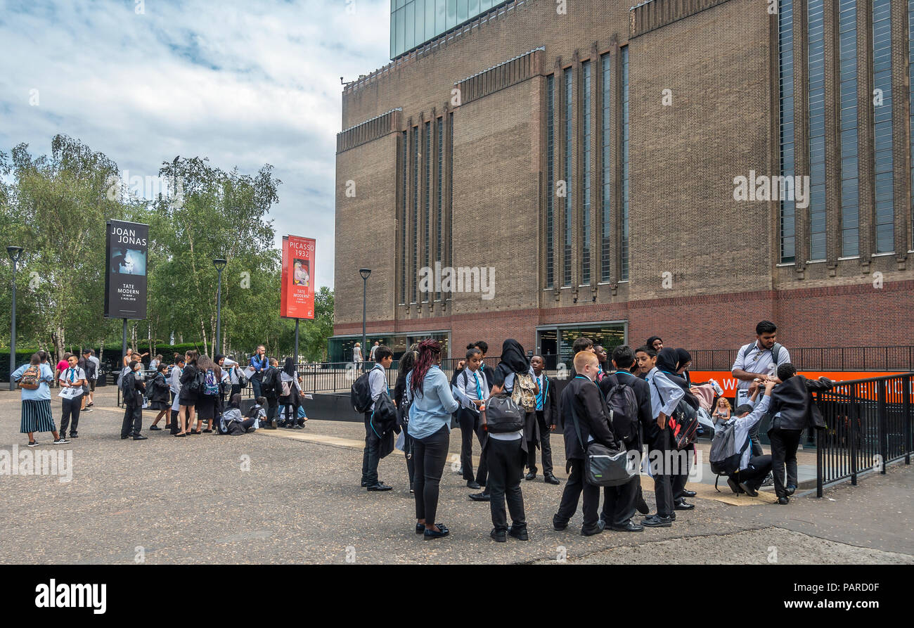 Deux groupes d'enfants de l'école avec leurs enseignants attendent pour entrer la Tate Modern Art Gallery de Londres. Certains utilisent des feuilles de travail. Banque D'Images