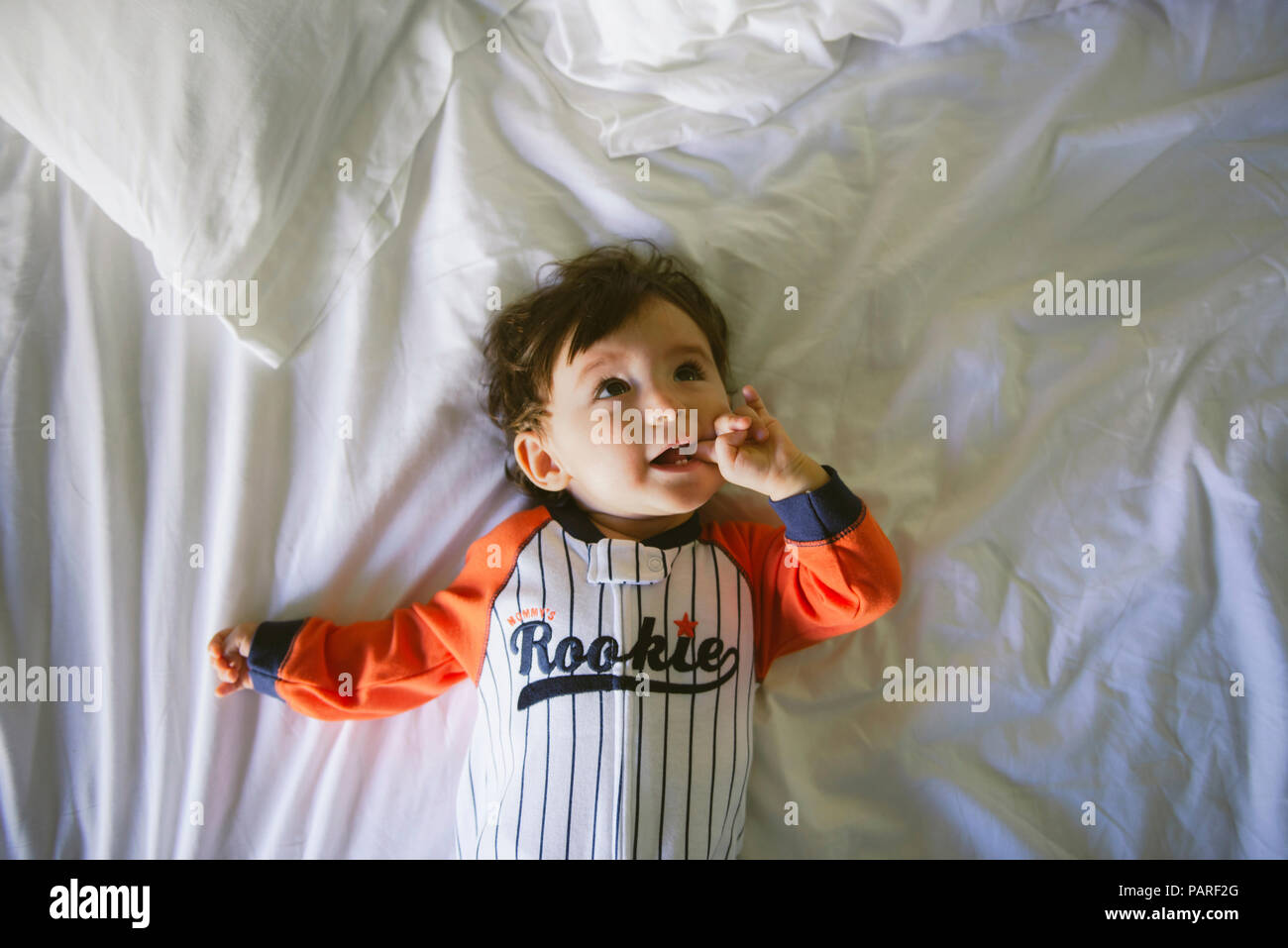 Portrait of baby girl wearing jumpsuit lying on bed Banque D'Images