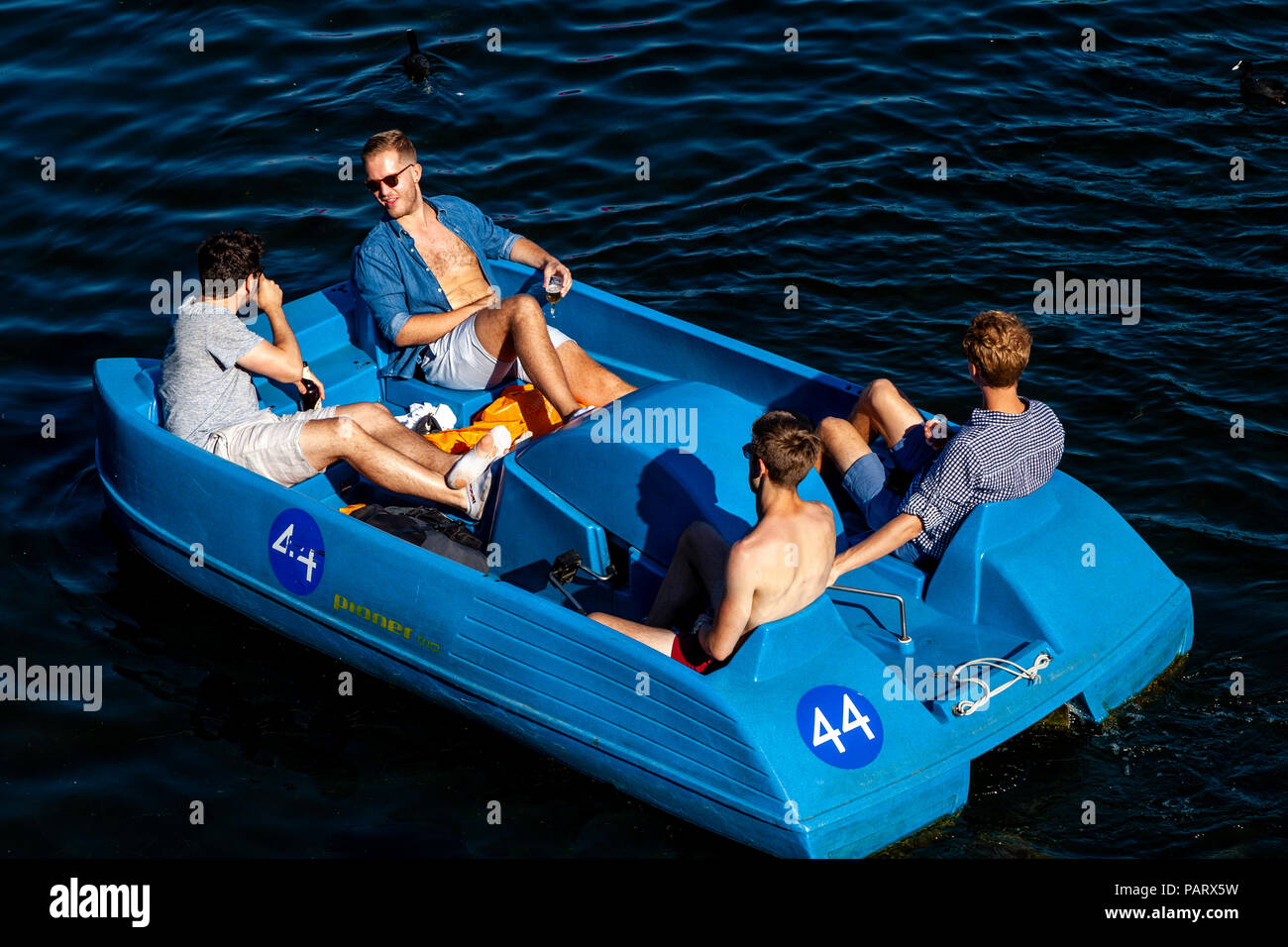 Quatre jeunes hommes se détendre dans un pédalo, la serpentine, à Hyde Park, Londres, Angleterre Banque D'Images