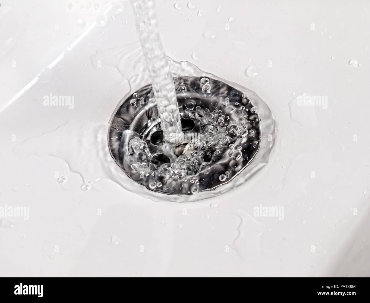 Gros plan du fonctionnement de l'eau dans un lavabo en céramique blanche vidanger Banque D'Images