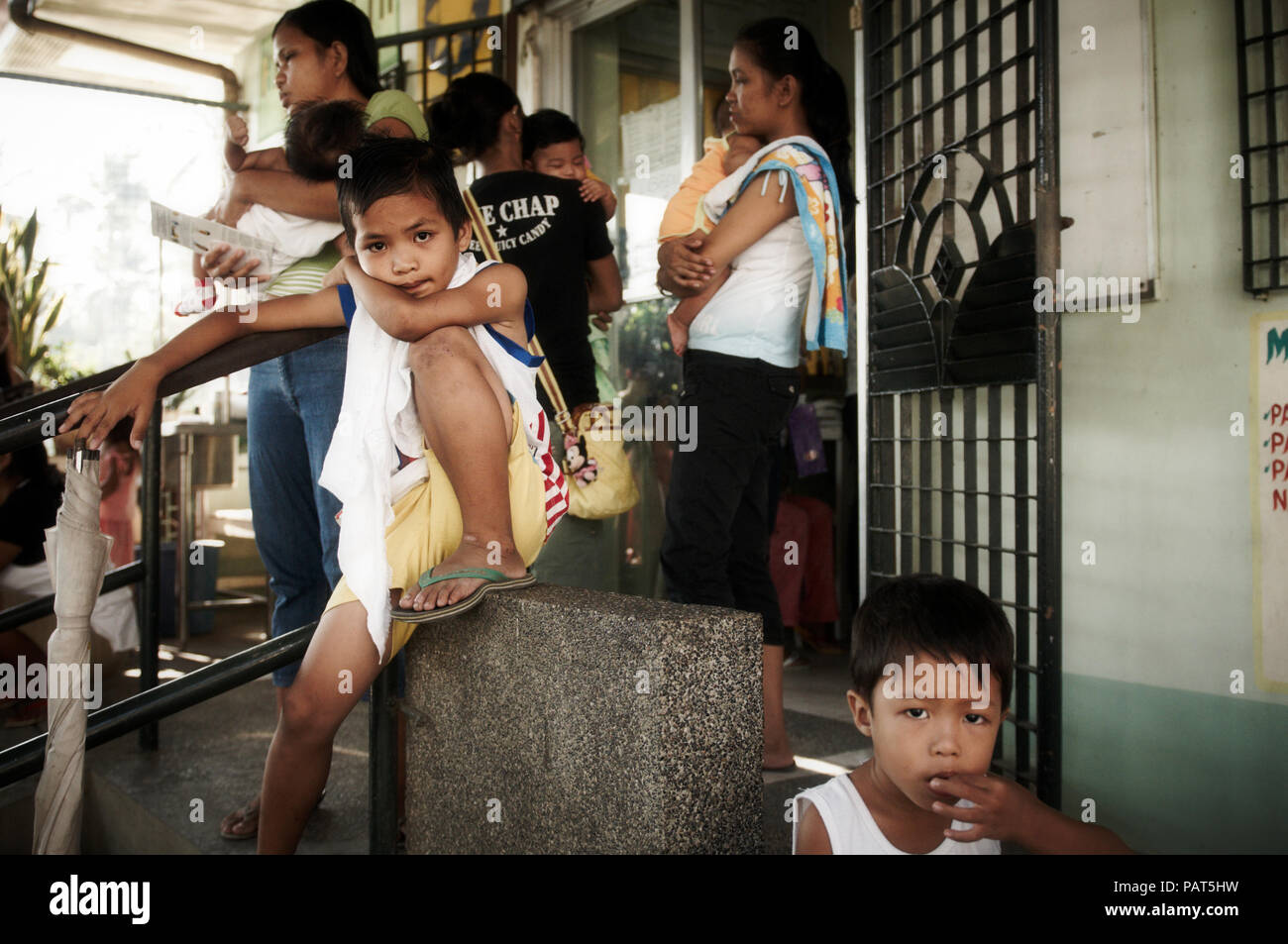 Les enfants et les mères d'attendre à l'extérieur de la clinique de santé maternelle pour le traitement. Banque D'Images