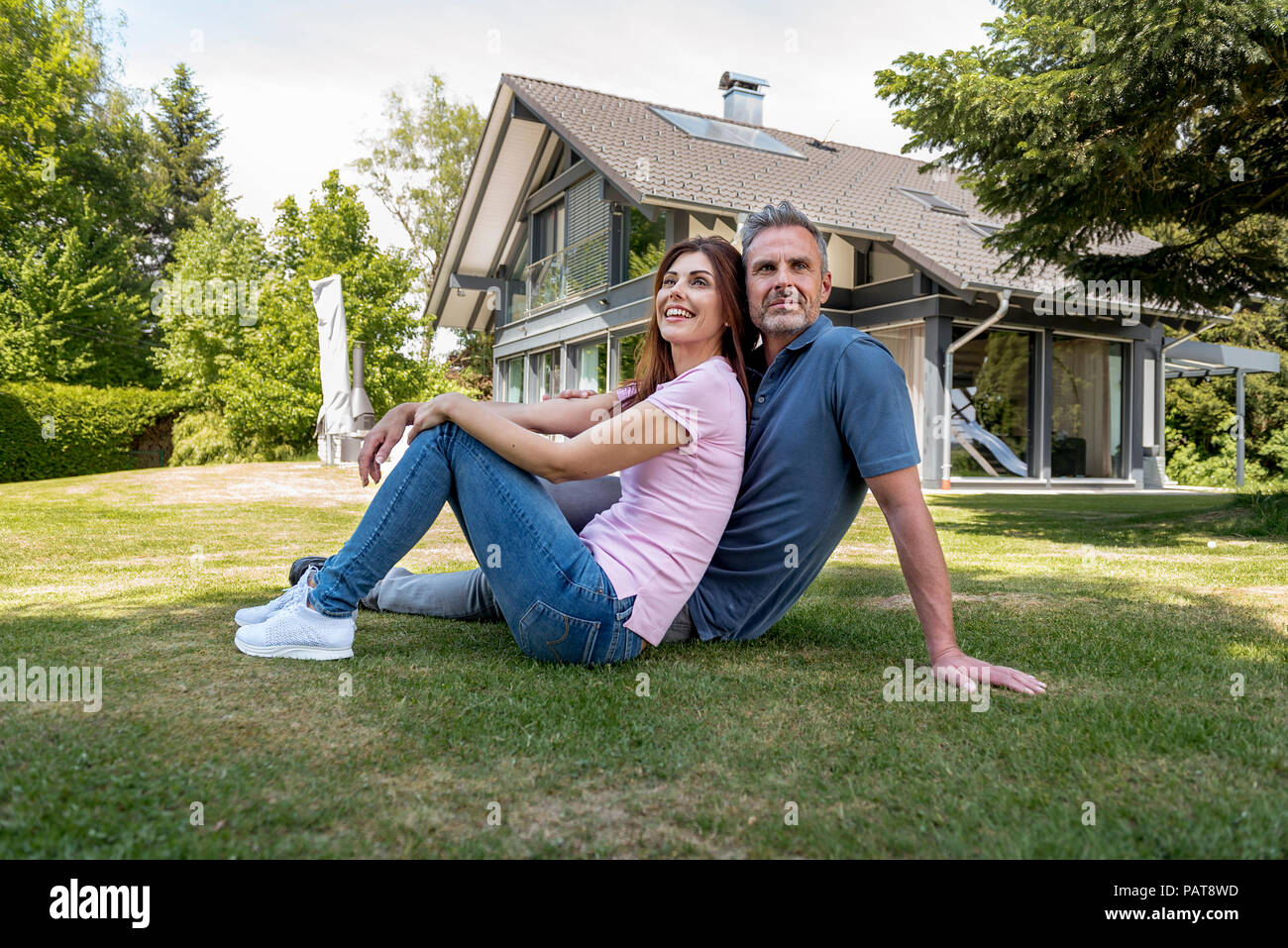 Heureux couple assis dans le jardin de leur maison Banque D'Images