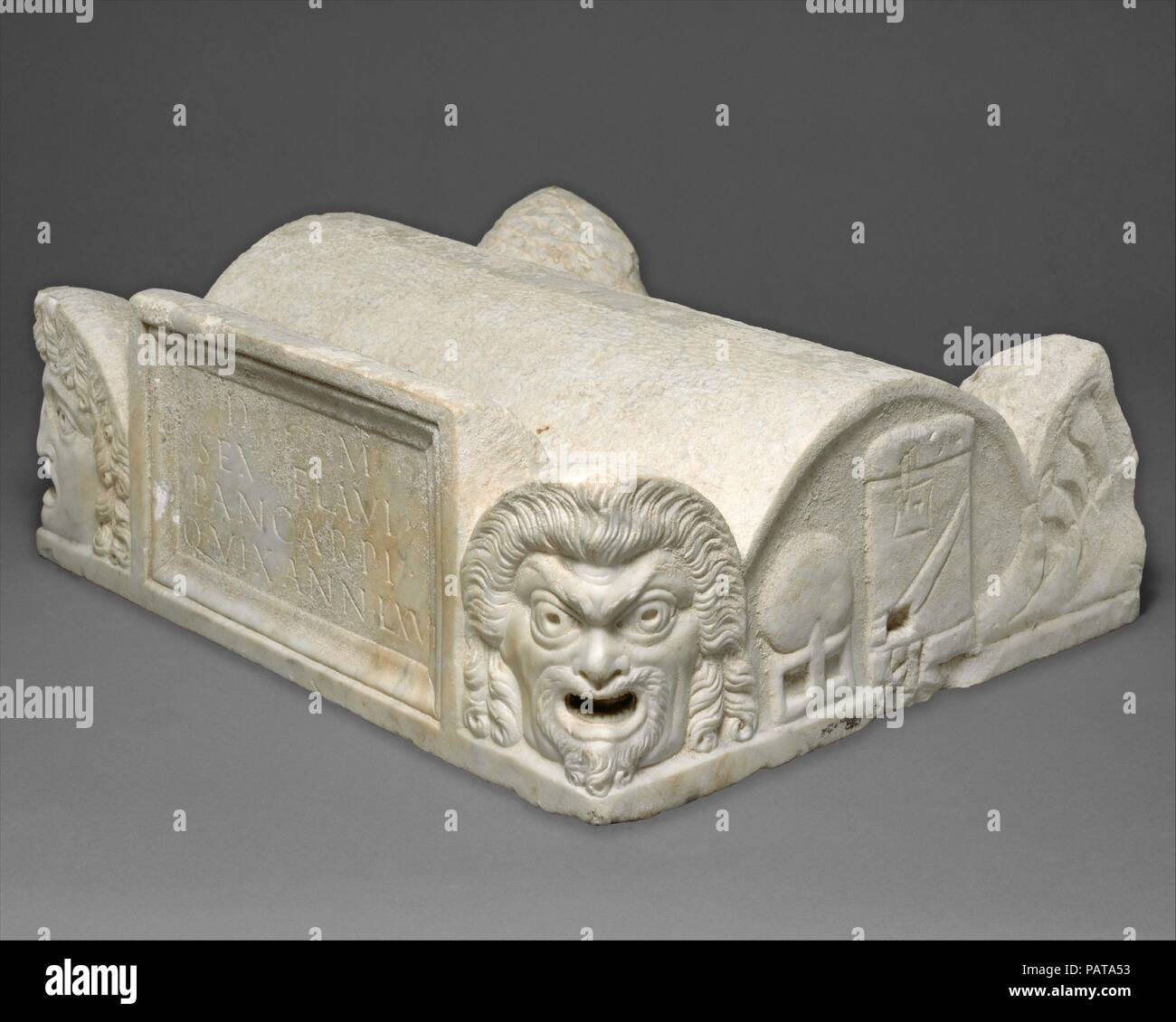 En couvercle d'une poitrine cinéraire. Culture : Roman. Dimensions : hors tout : 6 5/8 x 19 1/2 x 16 1/4 in. (16,8 x 49,5 x 41,3 cm). Date : fin du 1er siècle de notre ère. Le couvercle est façonné pour ressembler au toit d'un bâtiment avec des voûtes en acroteria aux coins sous la forme de masques de théâtre et de palmettes. Le panneau avant est inscrit en latin : "aux esprits des morts, [de] Pancarpus Sextus Flavius, qui a vécu 67 ans." Malgré le fait que l'inscription ne mentionne qu'un homme, l'lunettes sur les côtés montrent tant les hommes (globe et fort de morte) et femelle (miroir et fusée) Attributs, indicati Banque D'Images