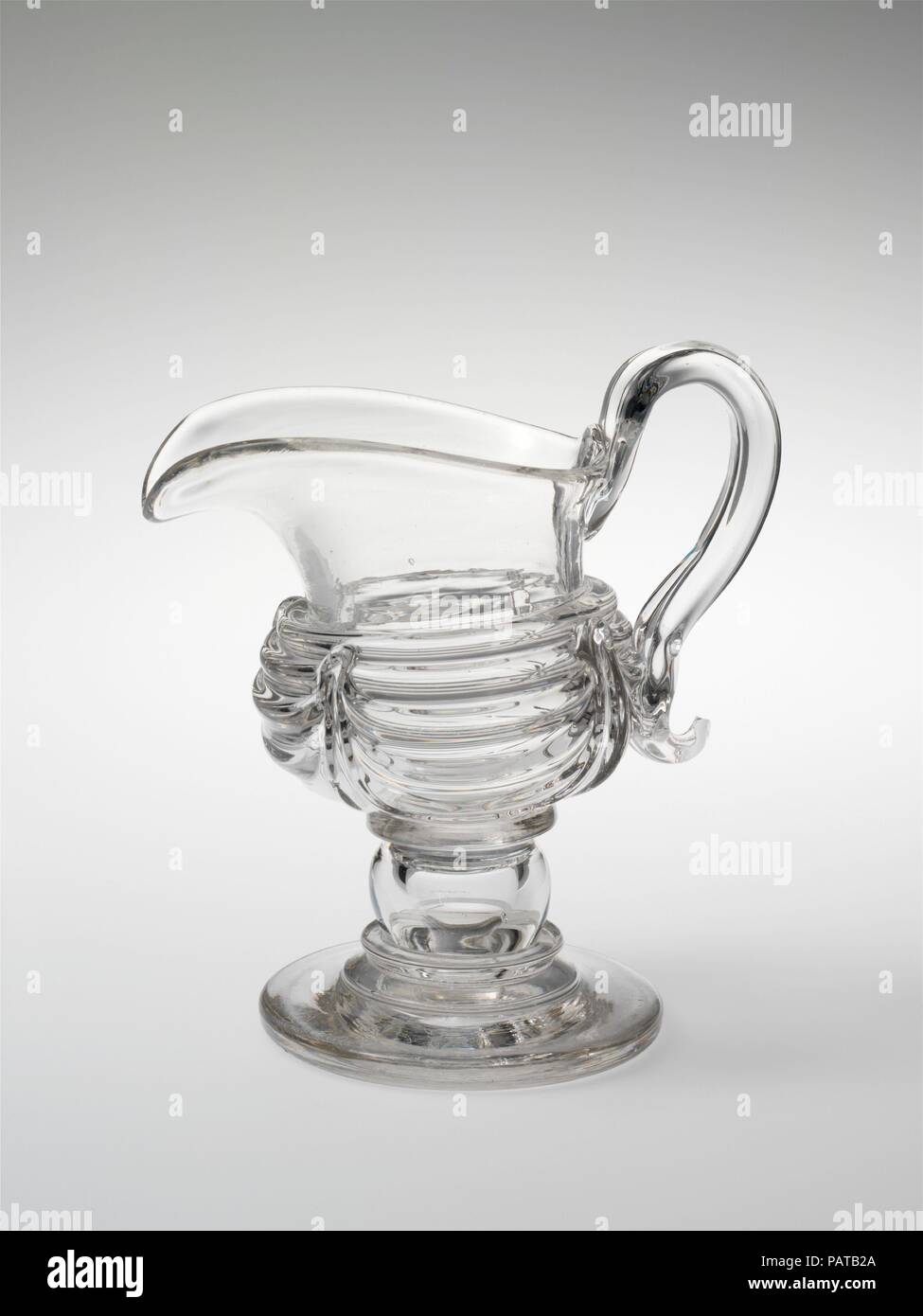 Pichet de crème. Culture : L'Américain. Dimensions : 6 1/16 x 5 9/16 in. (15,4 x 14,1 cm). Bouilloire : attribuée à New England Glass Company (Américain, East Cambridge, Massachusetts, 1818-1888) ; peut-être en verre de South Boston fonctionne. Date : 1815-35. Verre, couper finement gravés ou dans une variété de modèles basés sur les styles Régence anglaise, a été en vogue pour un art de la table au début du xixe siècle. Cet élégant pichet de crème et son bol de sucre révèlent une alternative à la découpe : la manipulation de la liquide clair, le verre dans son état fondu. Les navires de la moissonneuse-batteuse multipl Banque D'Images