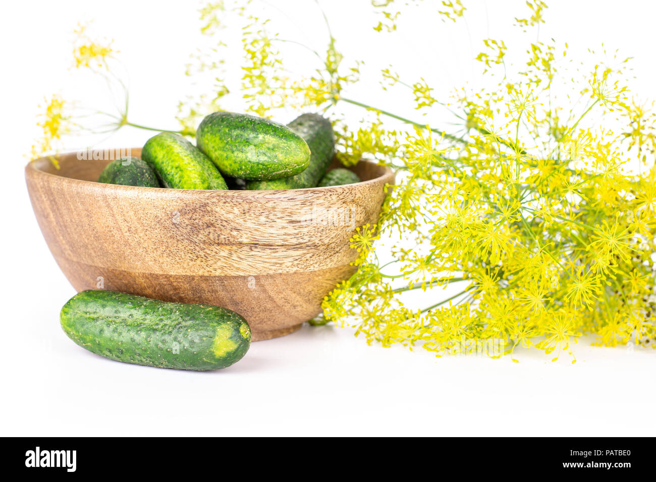 Beaucoup d'aneth frais entier et fleurs jaune bol en bois plein de concombres isolated on white Banque D'Images