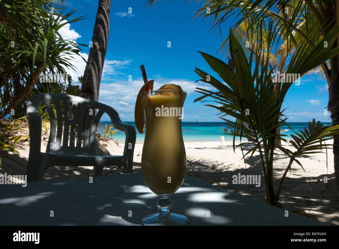 Mango shake sur la table du déjeuner à l'ombre, avec une mer turquoise en fond - Bounty Beach sur l'île de Malapascua, Cebu - Philippines Banque D'Images