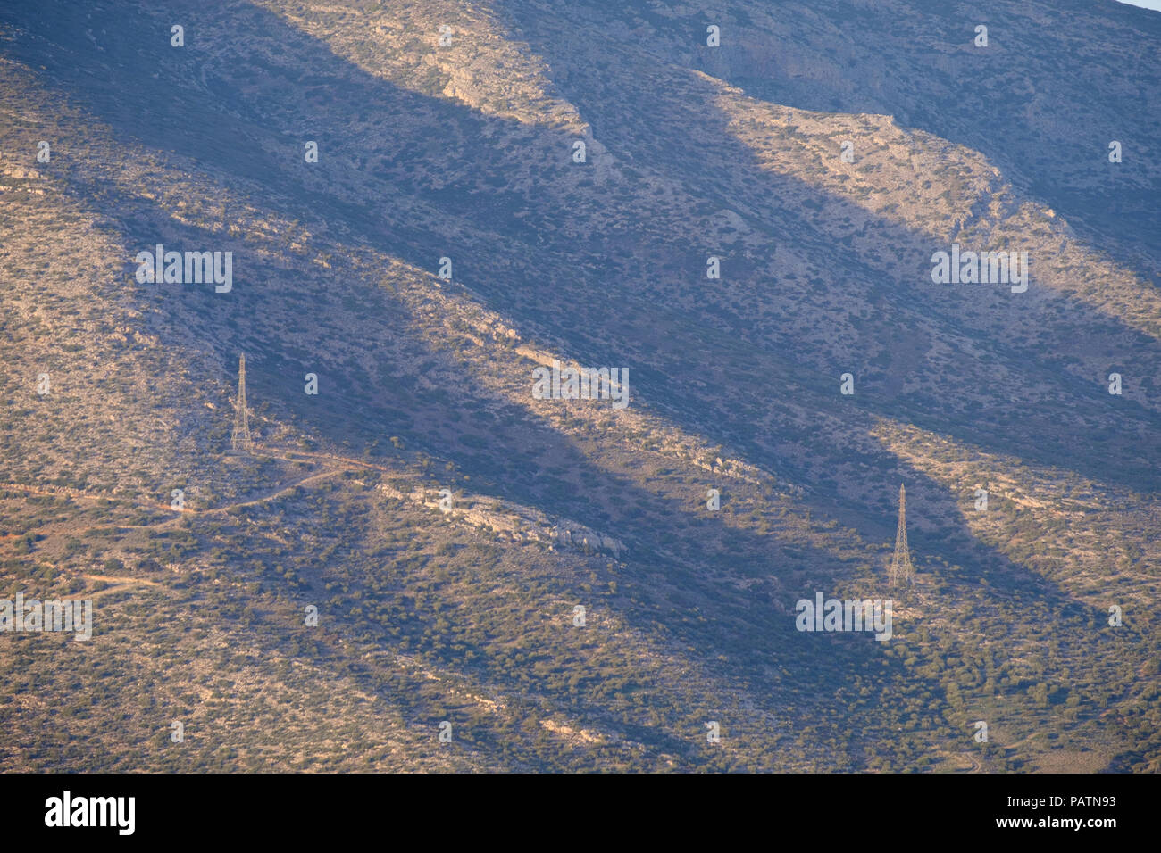 Lagonissi ( Lagonizi ) du côté de la montagne, l'ombre des tours de la ligne d'alimentation avec des crêtes de l'accomplissement de l'électricité. L'attique de l'Est, la Grèce, l'Europe. Banque D'Images
