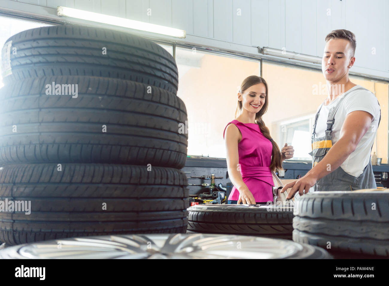 Beau mécanicien auto aider un client à choisir parmi différents pneumatiques Banque D'Images