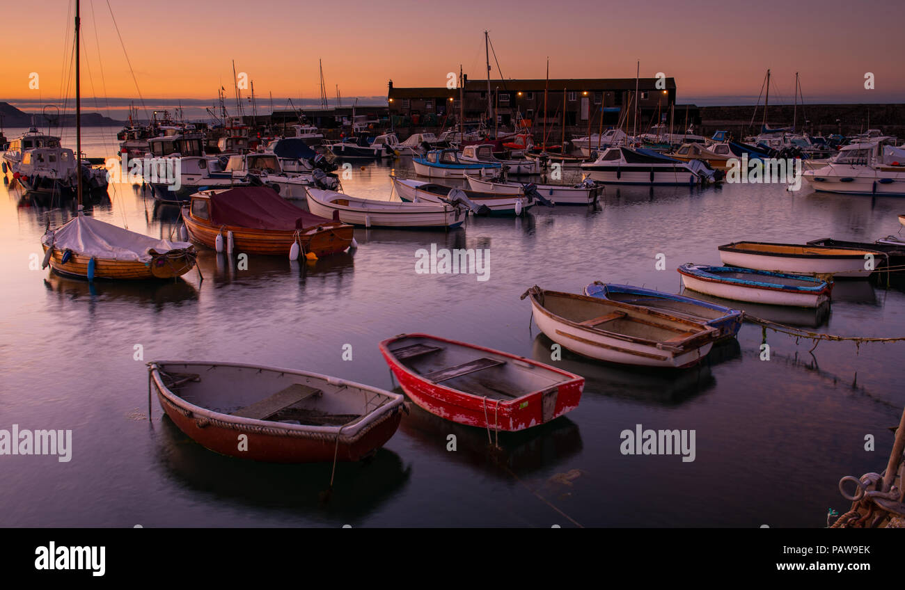 Lyme Regis, dans le Dorset, UK. 25 juillet 2018. Météo France : Golden sunrise à Lyme Regis. Les bateaux dans le port sont découpé sur la lumière dorée du petit matin ciel sur une autre journée chaude et ensoleillée dans la station balnéaire ville de Lyme Regis. Credit : Celia McMahon/Alamy Live News. Banque D'Images