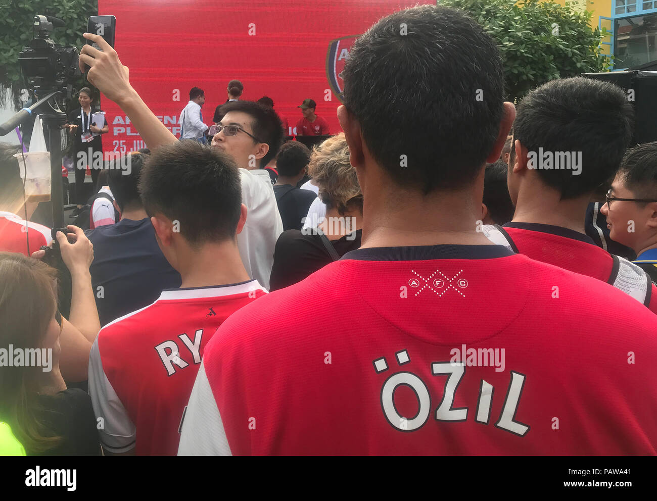 25 juillet 2018, à Singapour : football, Arsenal FC conférence de presse. Mesut Özil (arrière-R) se trouve sur le podium avec des coéquipiers alors que quelqu'un dans l'assistance porte un maillot avec le nom de l'actrice allemande sur son dos. Arsenal FC est actuellement sur un tour de la publicité en Asie. Le club de Londres se réunira l'Atlético Madrid et Paris Saint-Germain en leur présence dans la ville du sud-est asiatique à l'état de la Coupe des Champions internationaux. Photo : Christoph Sator/dpa Banque D'Images