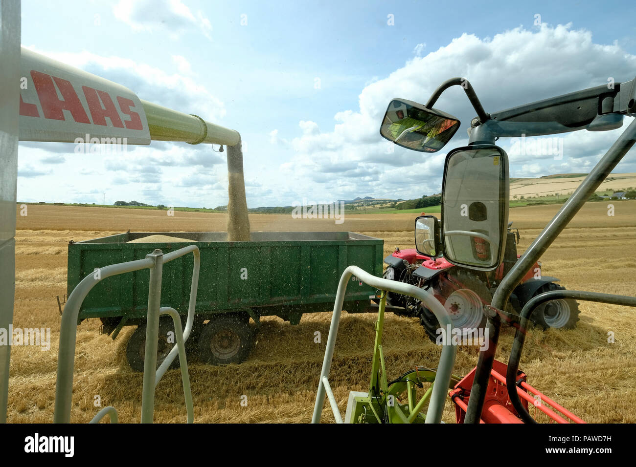 Kelso, Ecosse, 25 juillet 2018. Moissonneuse-batteuse dans Scottish Borders Tom Stewart de Sandyknowe Farm, près de Kelso dans les Scottish Borders, dans un rendmt Lexion Claas 660 Vario 770 avec barre de coupe à la moissonneuse-batteuse, qui travaillent dans les champs près de sa ferme, le mercredi 25 juillet 2018. Le transfert d'une culture à un tracteur d'attente pour passer à la ferme à quelques kilomètres de là. (Photo de Rob Gray / offres de crédit) : Rob Gray/Alamy Live News Banque D'Images