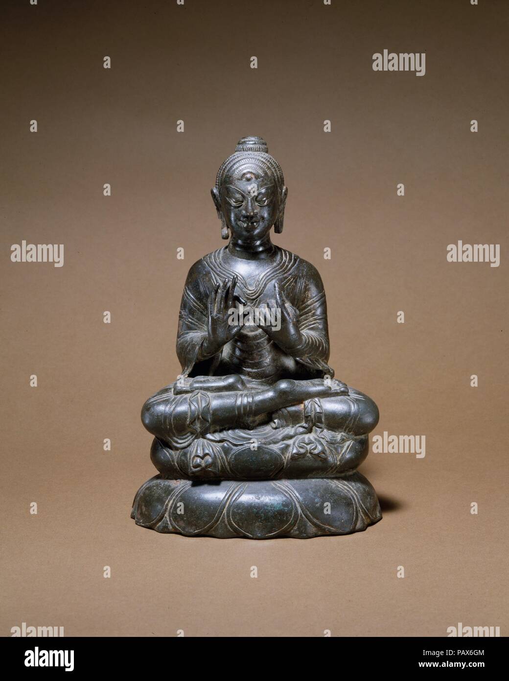 La prédication de Bouddha. Culture : l'Inde (Jammu-et-Cachemire, ancien royaume du Cachemire) ou le Pakistan. Dimensions : H. 8 3/8 in. (21,3 cm). Date : 8ème siècle. Ce Bouddha, avec ses jambes repliées dans un posture yogique complète et ses mains aux gestes la prédication, appelle le premier sermon à Sarnath. Le traitement complexe des robes monastiques, et tout particulièrement leurs extrémités plissées, est la preuve d'un atelier monastique non identifié, probablement situé dans le Cachemire ou la vallée de Swat. Le traitement des boucles de cheveux est non conventionnel, comme c'est la stylisation extrême des yeux et sourcils. Incrustation d'argent marque le yeux et auspicio Banque D'Images