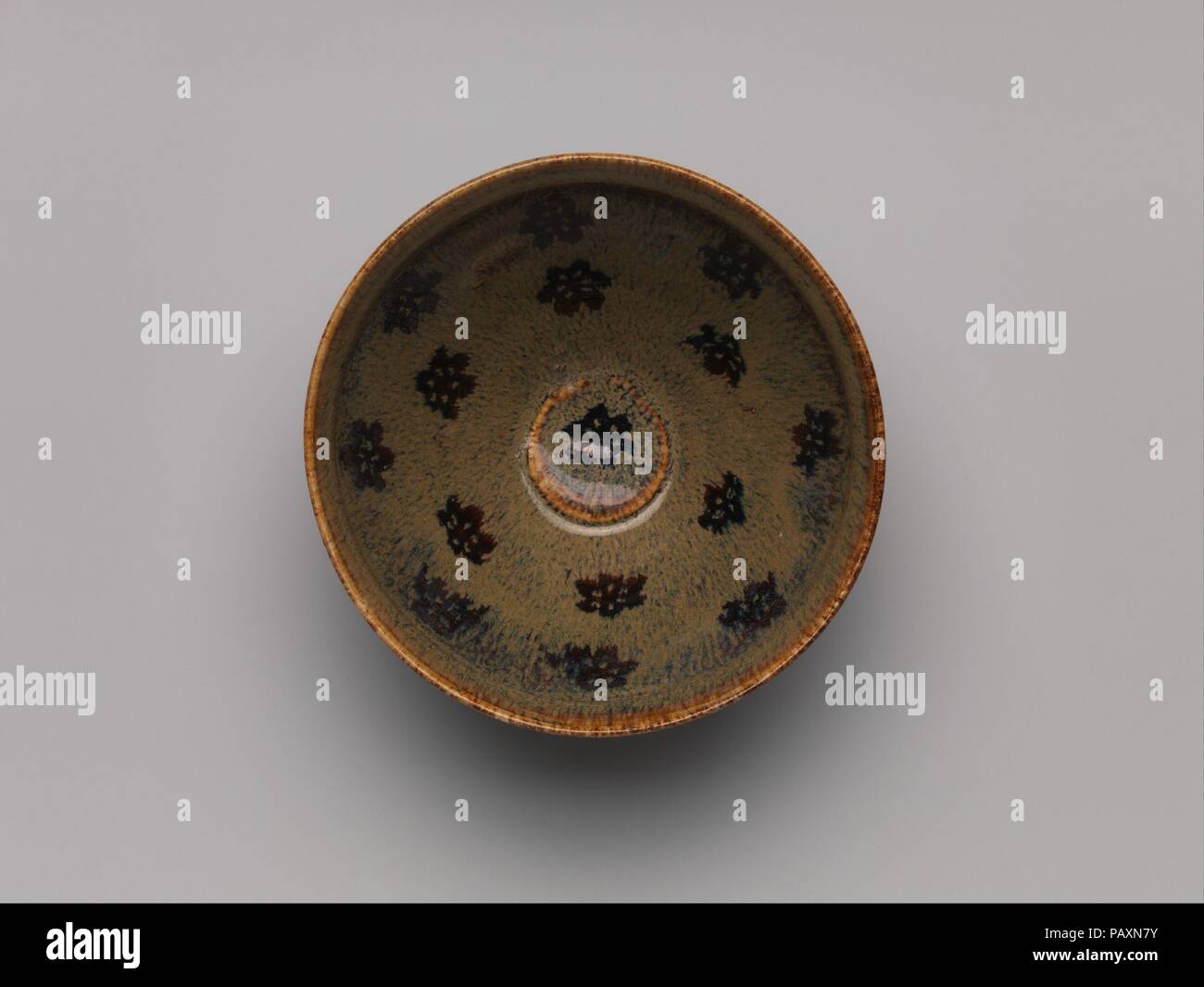 Bol à thé à décor de six pétales de fleurs. Culture : la Chine. Dimensions : H. 2 5/8 in. (6,7 cm) ; Diam. 5 in. (12,7 cm). Date : 12ème-13ème siècle. Note pour l'originalité de dessins industriels et techniques innovantes, Jizhou ware a été produit à fours dans la province de Jiangxi, dans le sud de la Chine. Ici, le papier-cut plum blossoms ont été placés sur une première couche de glacis noir et recouvert d'émail marron. Les coupures ont été détruits pendant le tir, laissant la conception de fleurs de prunier à l'intérieur de la cuve. Note pour l'originalité de dessins industriels et techniques innovantes, Jizhou ware a été produit lors de fours Banque D'Images