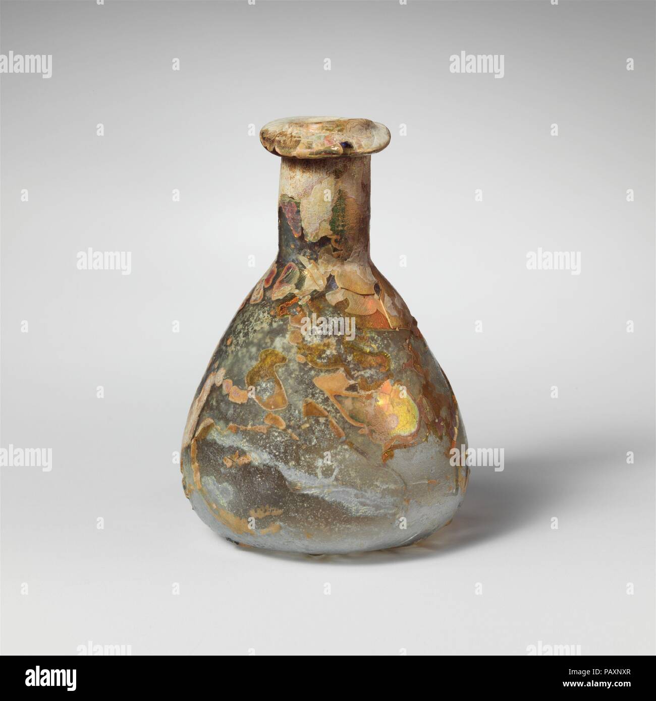 Flacon de parfum en verre. Culture : Roman. Dimensions : hors tout : 2 3/4 in. (7 cm) Diam. : 2 x 7/8 in. (5,1 x 2,2 cm). Date : 1er siècle de notre ère. Bleu pâle translucide vert. Jante inégale déployés, plus de, et dans le cou cylindrique court ; outillage avec tiret autour de base ; corps conique, arrondies à la base ; fond plat. Des traces de tiret horizontal autour de milieu de corps. Mais complète avec de nombreuses fissures internes ; bulles ; piqûres piqûre profonde et de ternissement, parcelles d'altération crémeuse avec de brillants irisés. Musée : Metropolitan Museum of Art, New York, USA. Banque D'Images