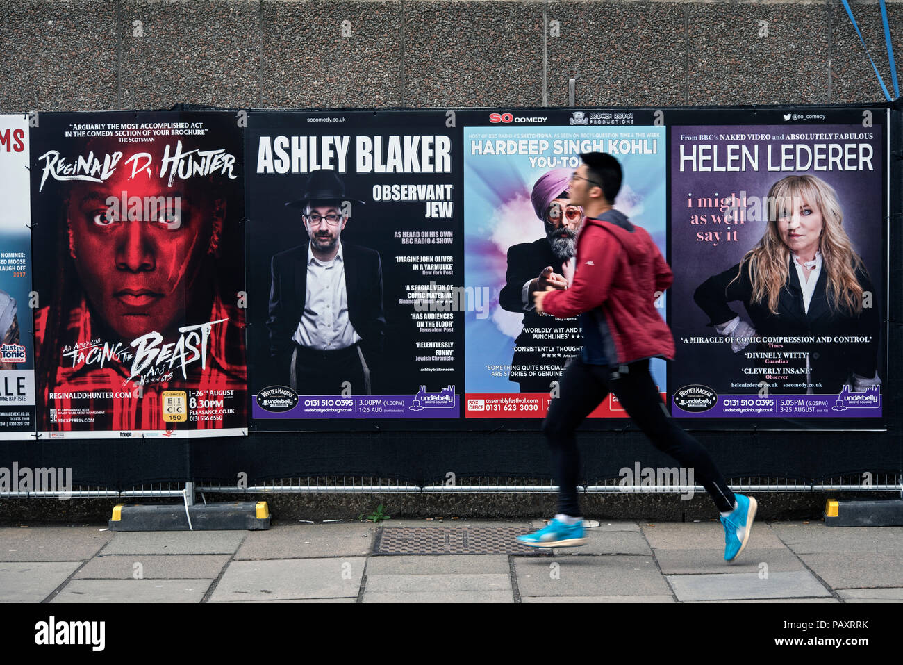 Jeune homme en marche par la publicité des affiches montre dans le Edinburgh Fringe Festival. Banque D'Images