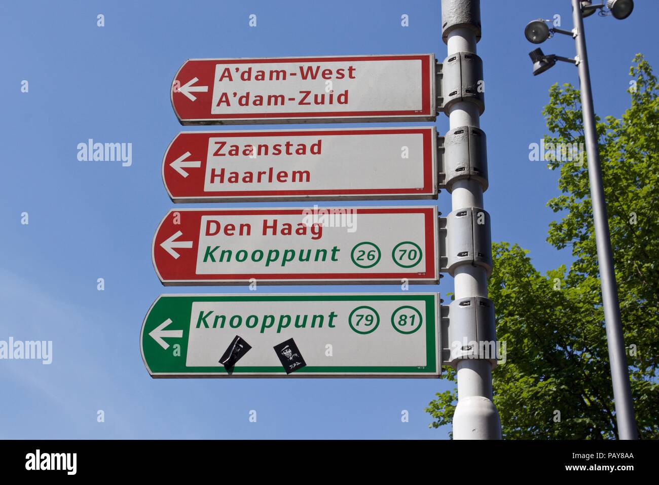 Quatre panneaux de direction Néerlandais à Amsterdam pour l'A'dam-Ouest, Zaanstad, Den Haag et Knooppunt Banque D'Images