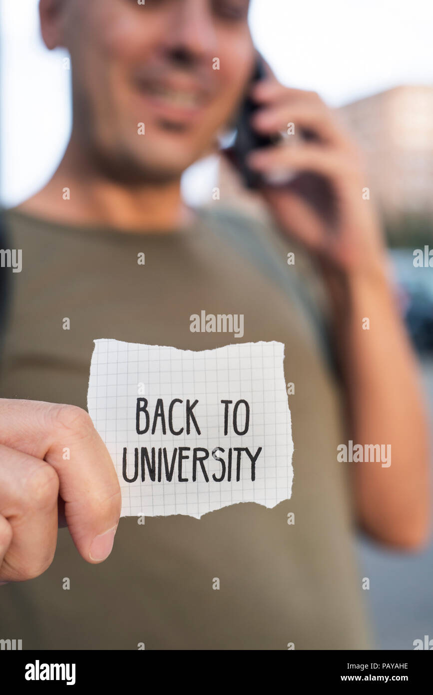 Libre d'un caucasian student guy en plein air montrant un morceau de papier avec le texte à l'université écrit en c Banque D'Images