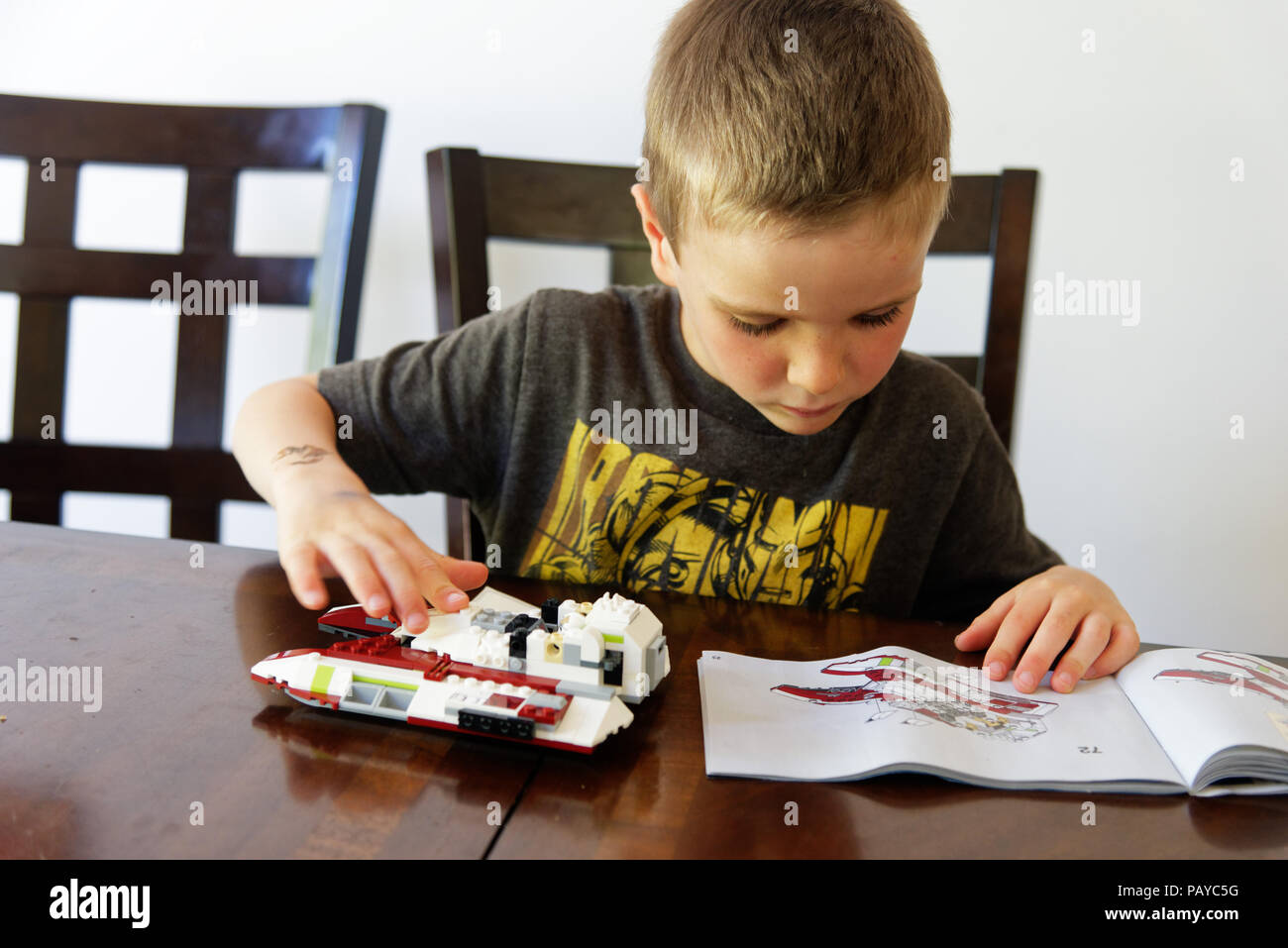 Un jeune garçon (6 ans) se concentrant sur faire ses Lego Star Wars fighter Banque D'Images