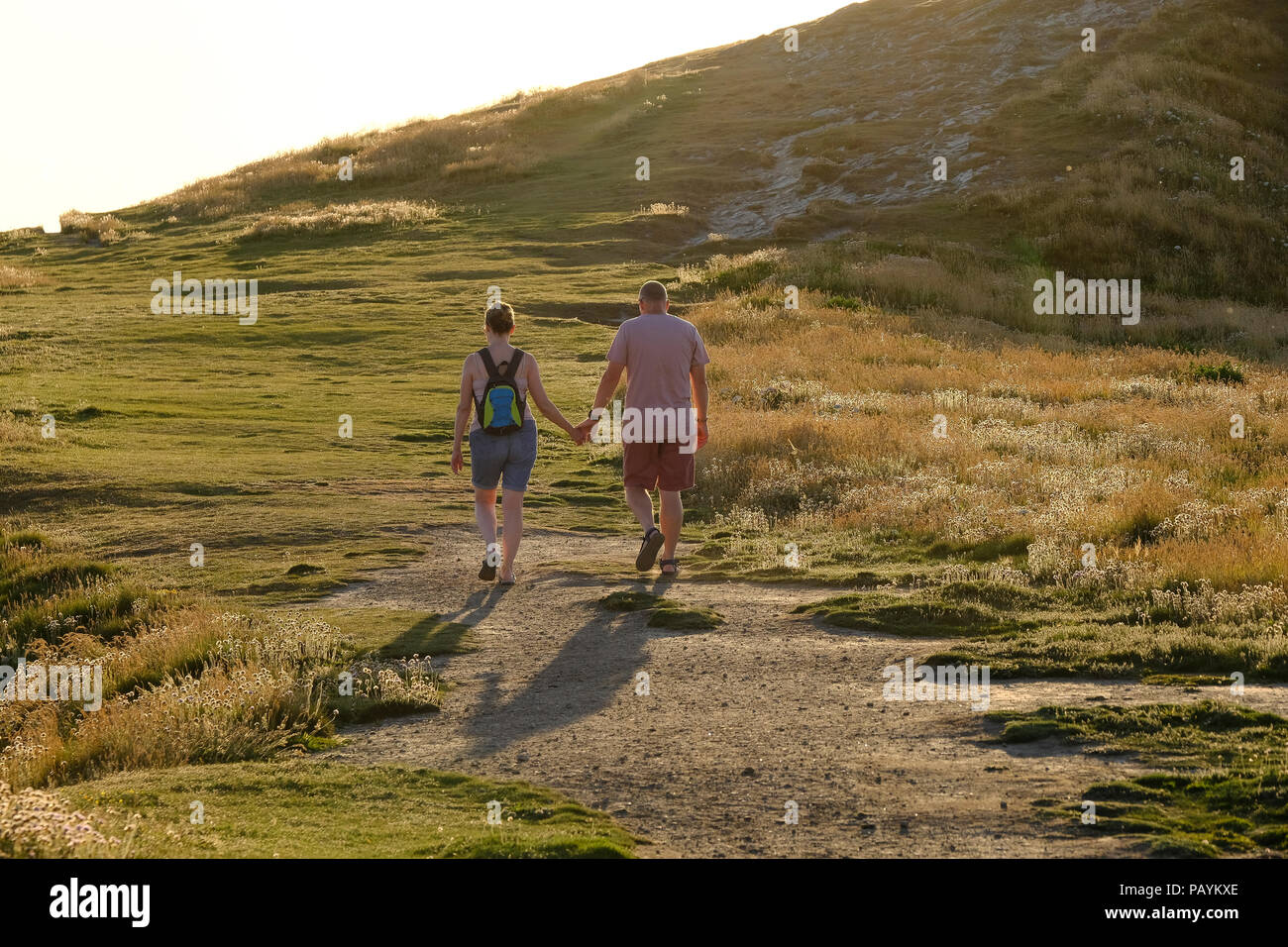 Un couple d'âge moyen tenant la main et marcher ensemble sur le chemin de la côte sud-ouest près de Newquay en Cornouailles Banque D'Images