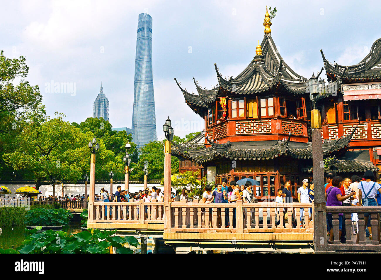 Shanghai, Chine, juillet 2015. Les gens qui marchent sur Jiuqu pont dans le jardin Yu Shanghai en une journée ensoleillée. La maison de thé Yuyuan et gratte-ciel à l'arrière-plan. Banque D'Images