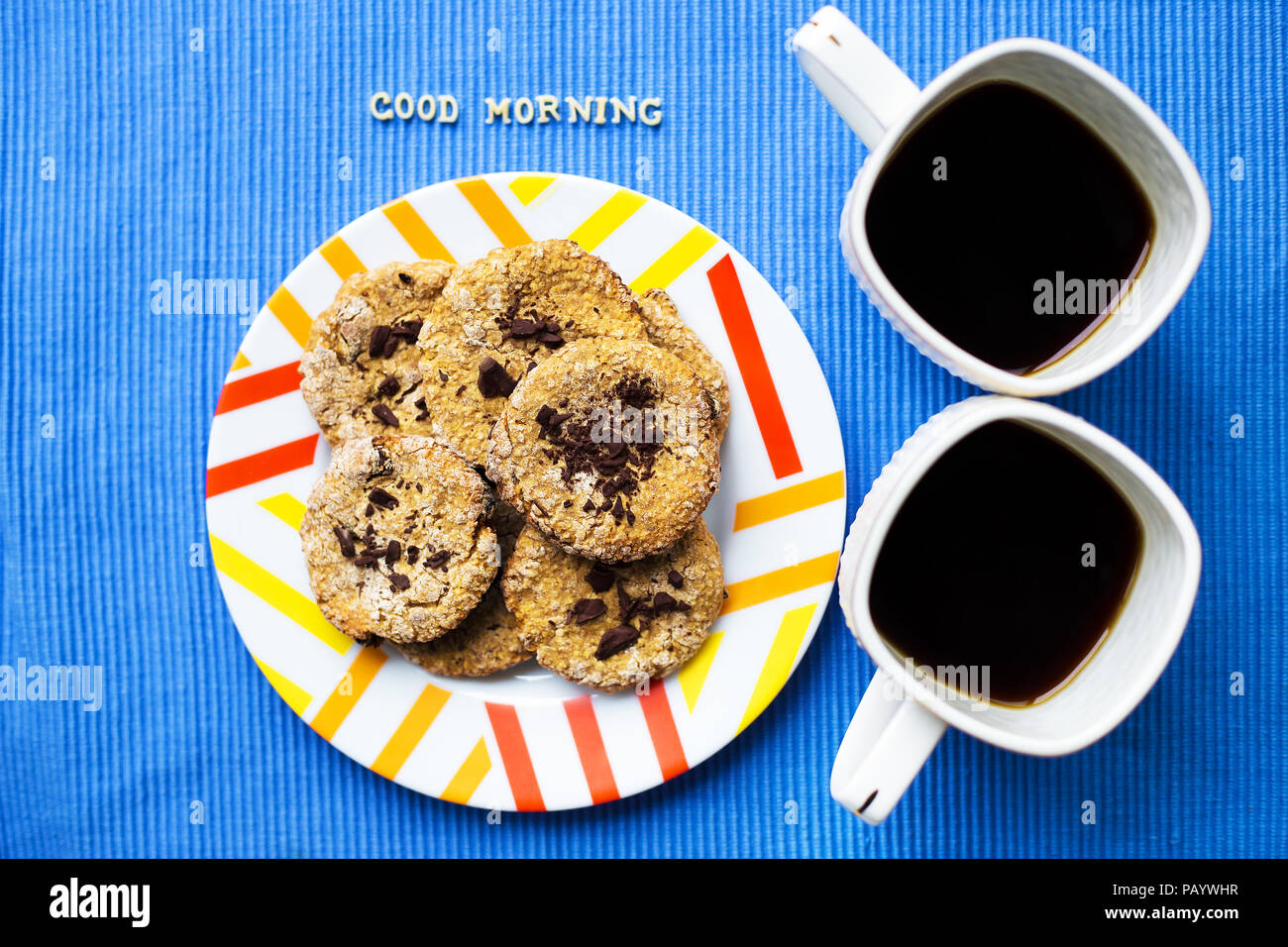 Oatmeal Cookies au chocolat sur fond bleu serviette et deux tasses de café, bonjour l'inscription Banque D'Images