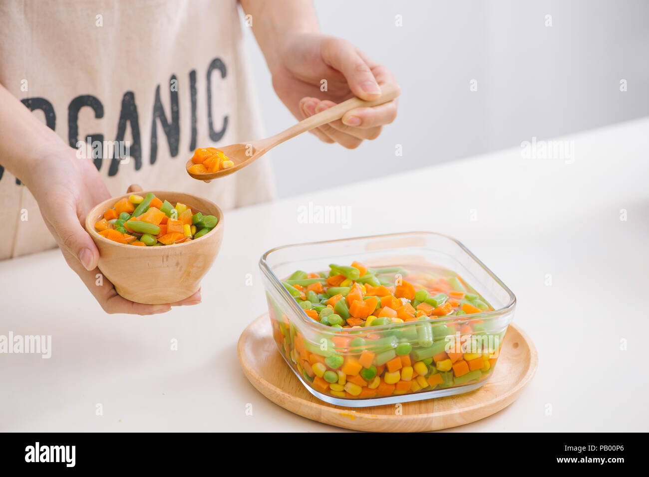Louche de jeunes légumes fraîchement récoltés à la vapeur y compris les carottes, en Coupe ondulée, de pois et de pommes de terre pour un accompagnement sain pour le dîner Banque D'Images
