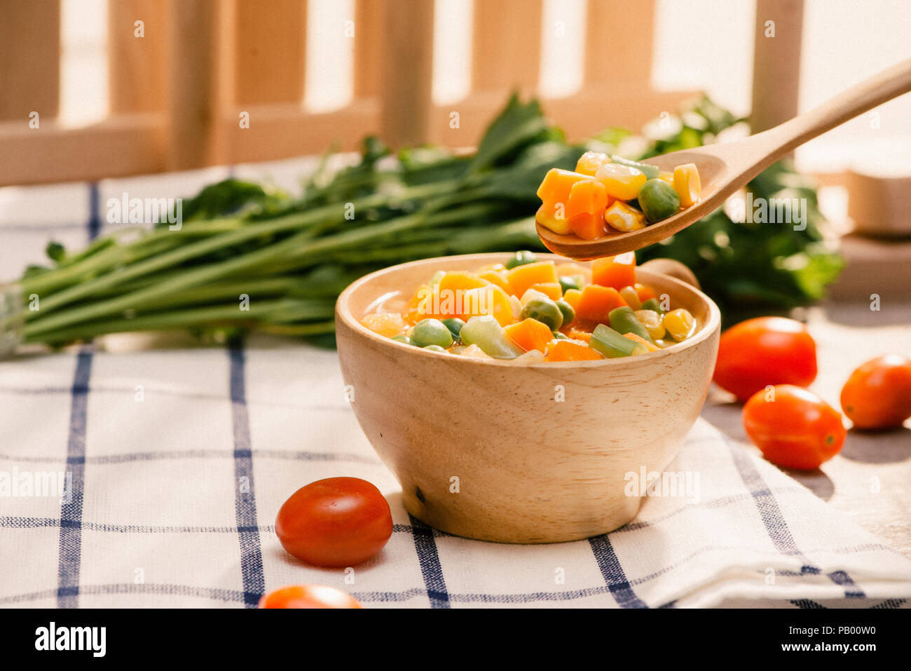 Louche de jeunes légumes fraîchement récoltés à la vapeur y compris les carottes, en Coupe ondulée, de pois et de pommes de terre pour un accompagnement sain pour le dîner Banque D'Images