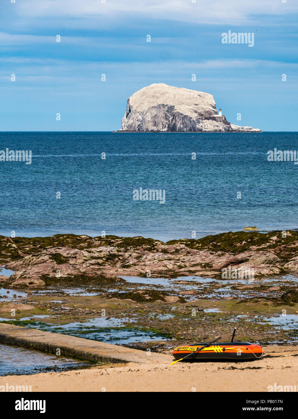 Bateau pneumatique bateau à rames sur plage avec Bass Rock et le phare à l'horizon blanc avec Bassan nicheurs, Milsey Bay, North Berwick, East Lothian, Scotland, UK Banque D'Images